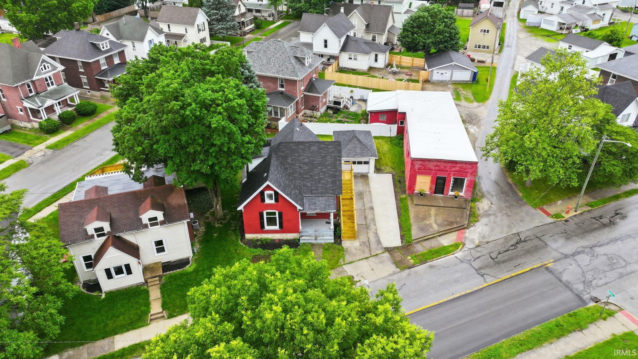 Aerial perspective showcasing a residential property with a distinctive red exterior and dark roofing