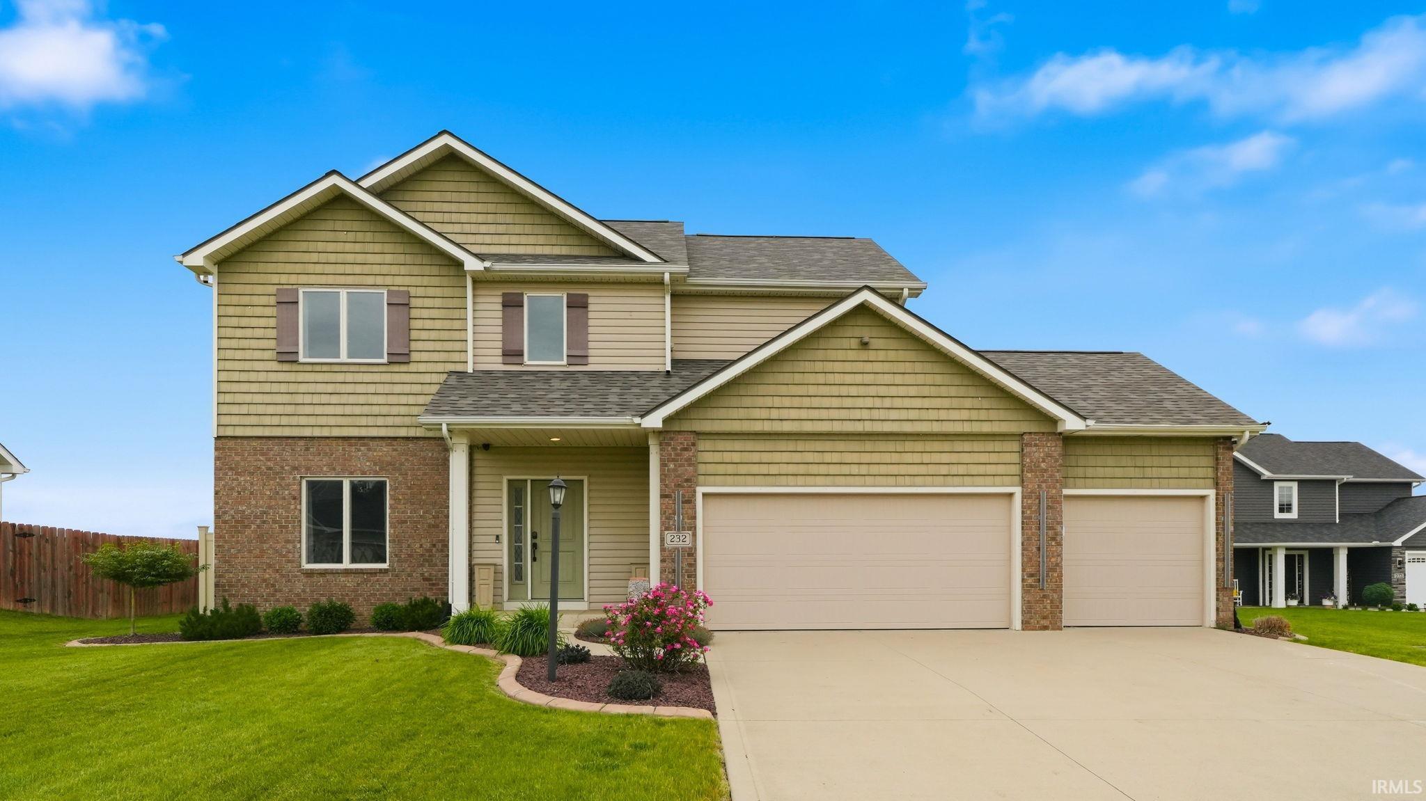 Two-story residence featuring a combination of brick and siding, a covered porch entry, and a two-car attached garage
