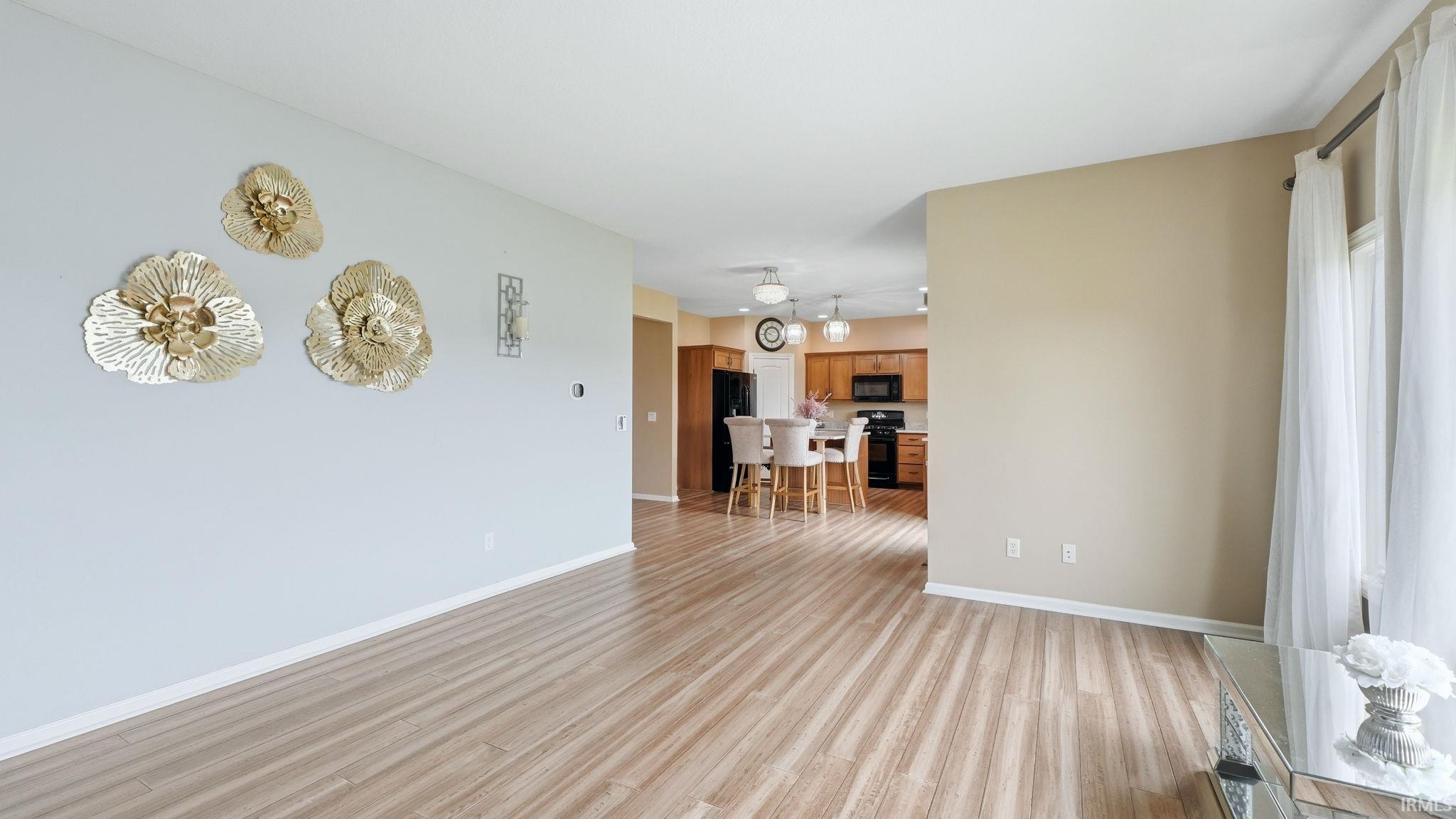 Open-concept living space featuring light wood-finish flooring, white baseboards, and neutral wall tones