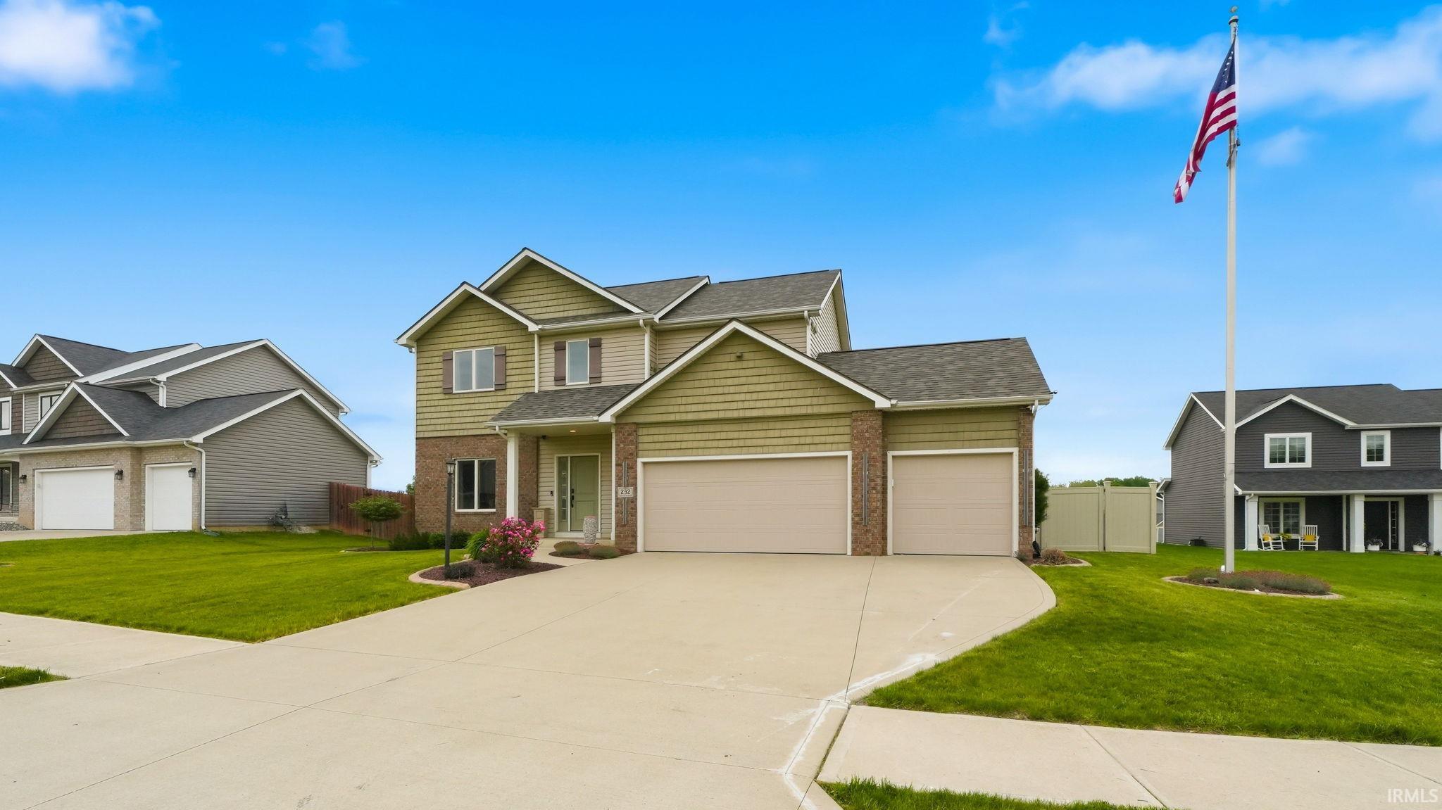 Two-story residence featuring a two-car garage, brick and siding exterior, and a concrete driveway