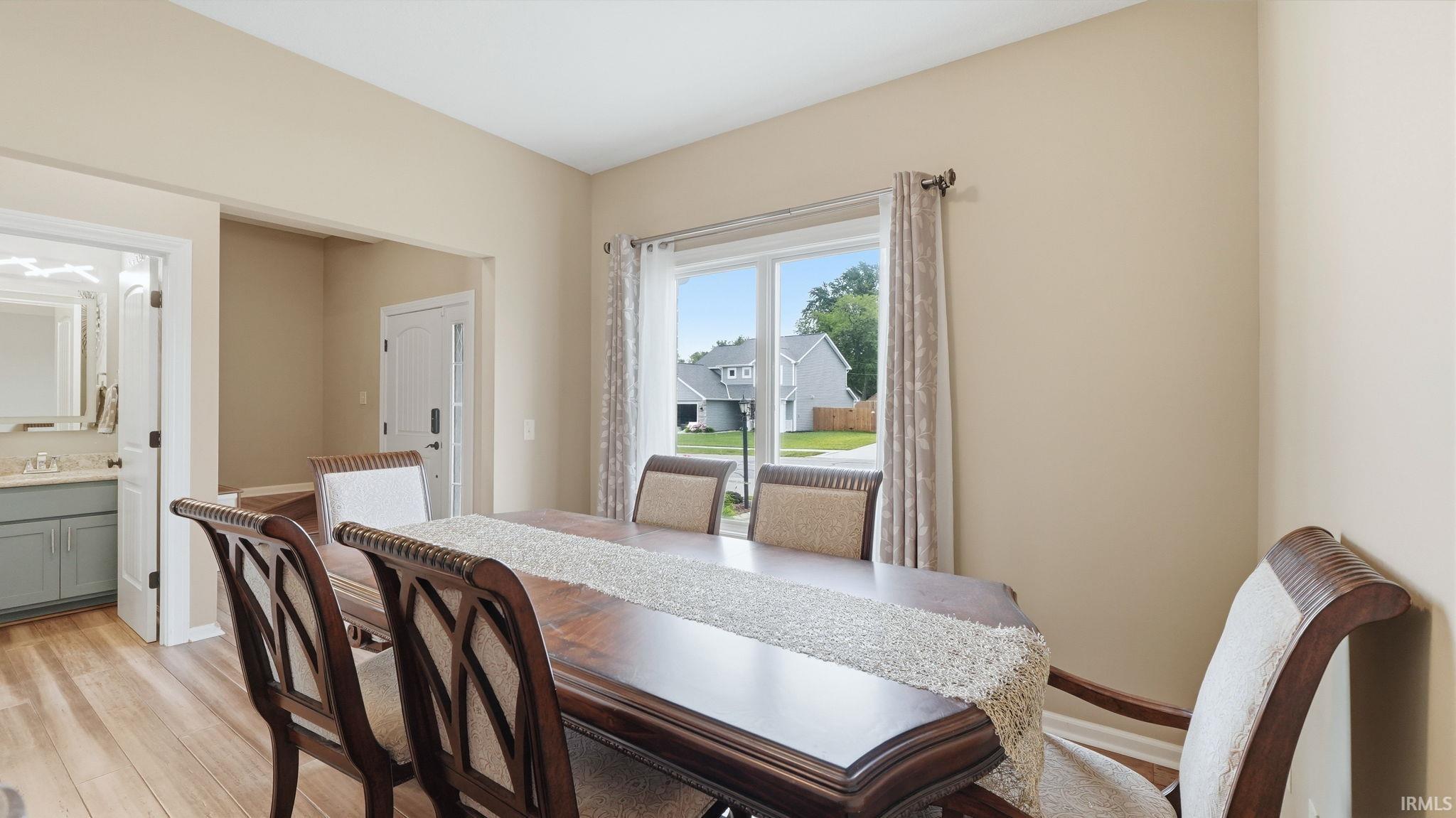 Dining area with wood-finish flooring, neutral wall paint, and a large window with curtain rod