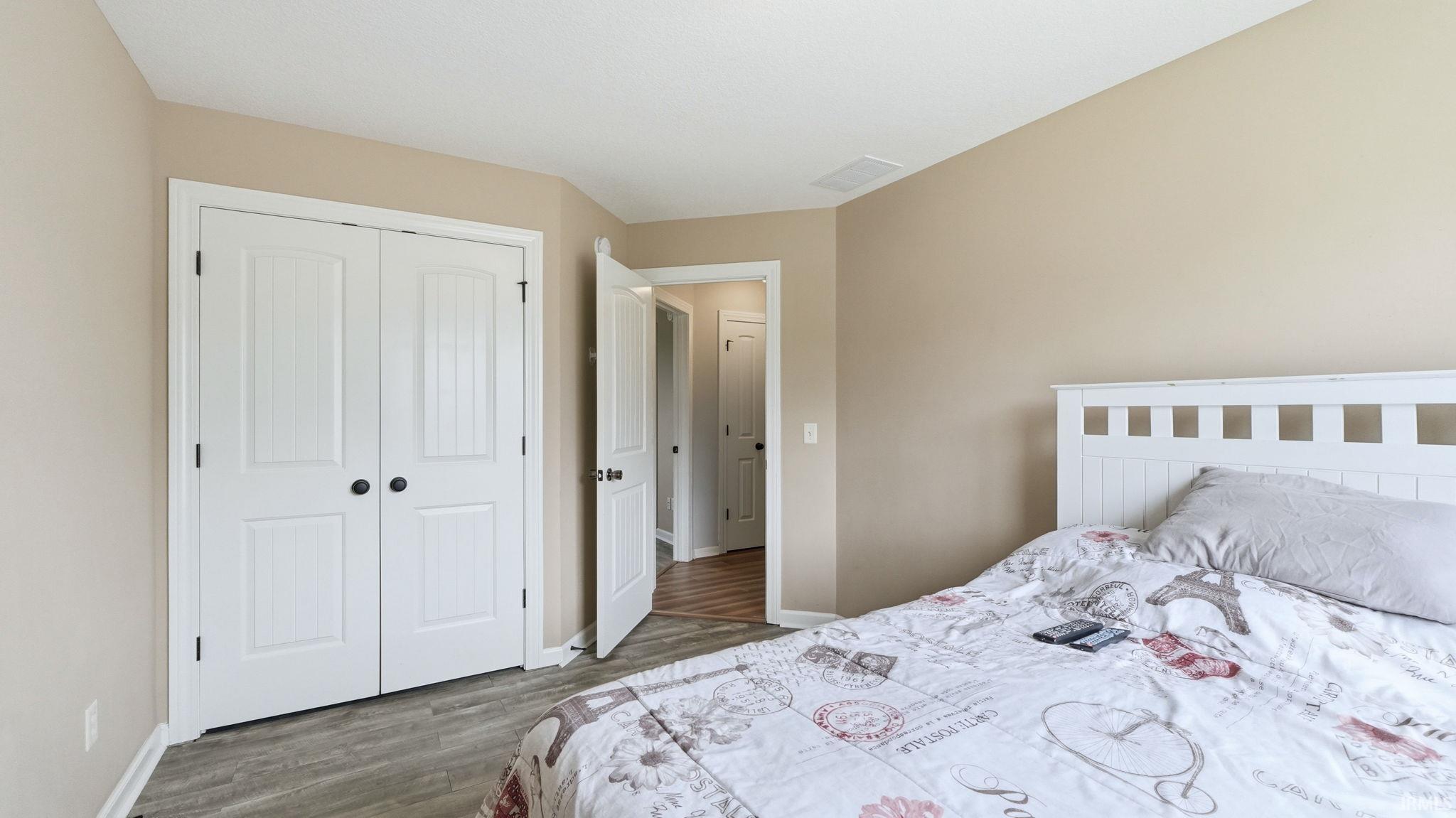 Bedroom featuring neutral wall paint, white trim, and wood-finish flooring