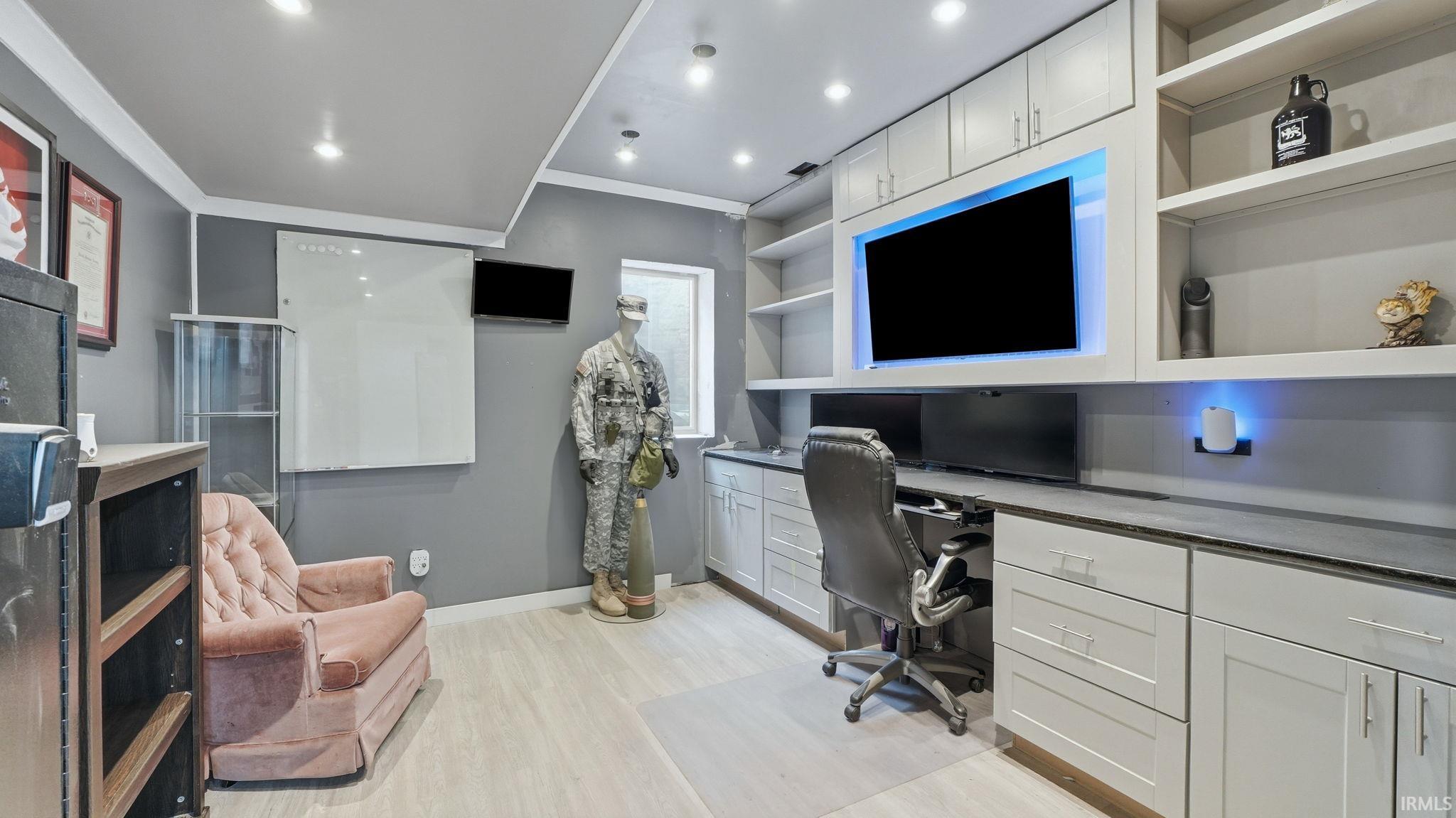 Dedicated workspace featuring extensive built-in cabinetry, integrated shelving, and a large wall-mounted monitor