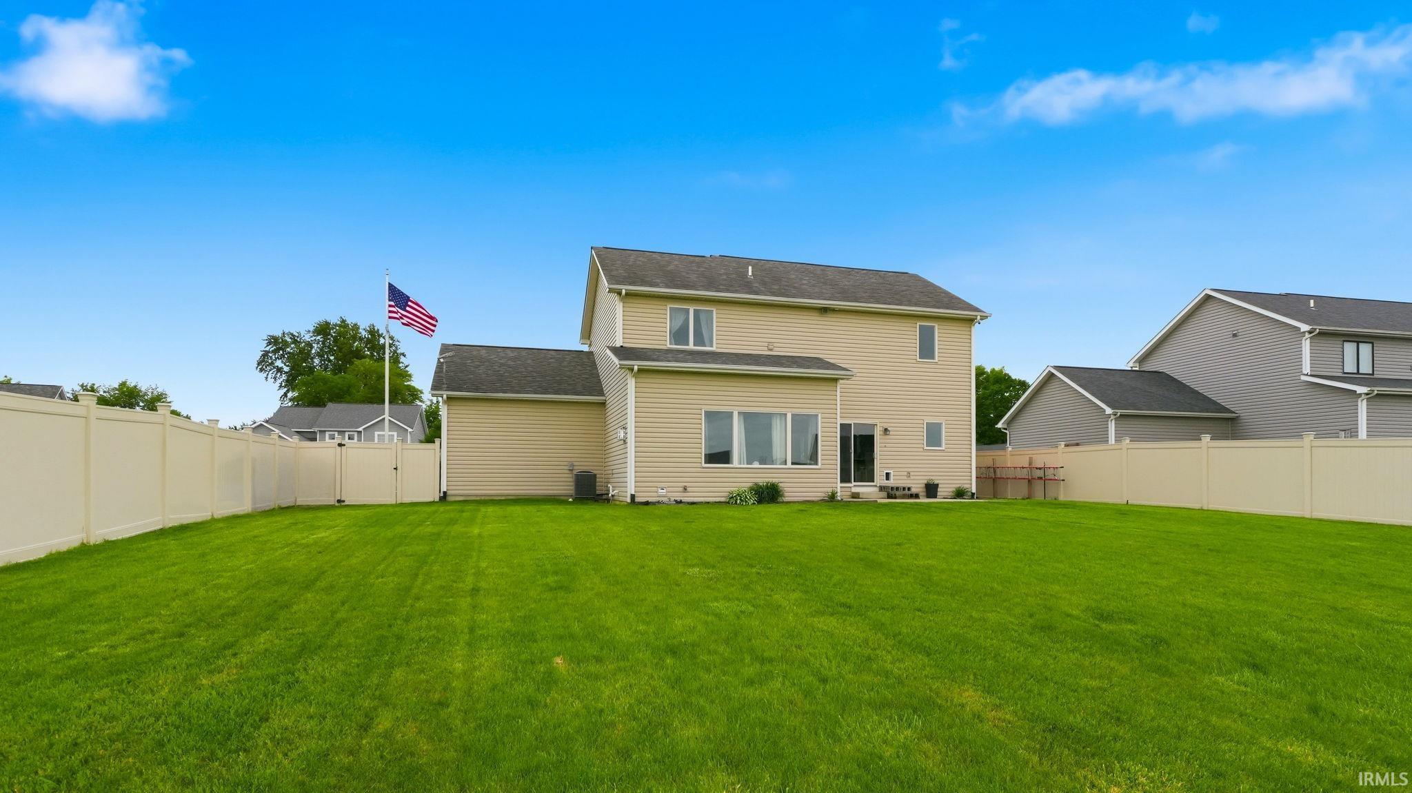 Expansive grassy yard enclosed by light-colored fencing