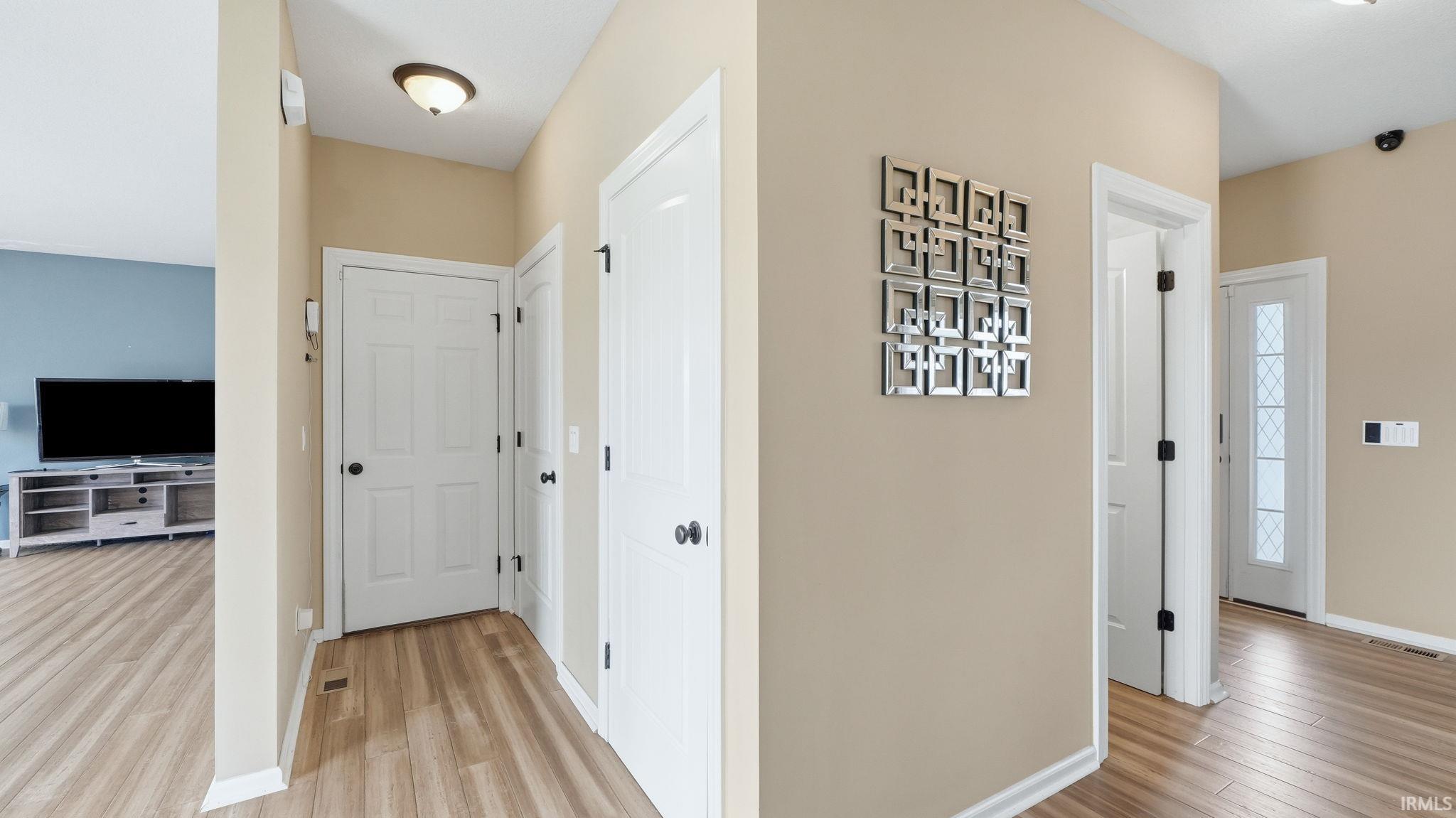 Entryway featuring wood-finish flooring, light tan wall paint, and white trim