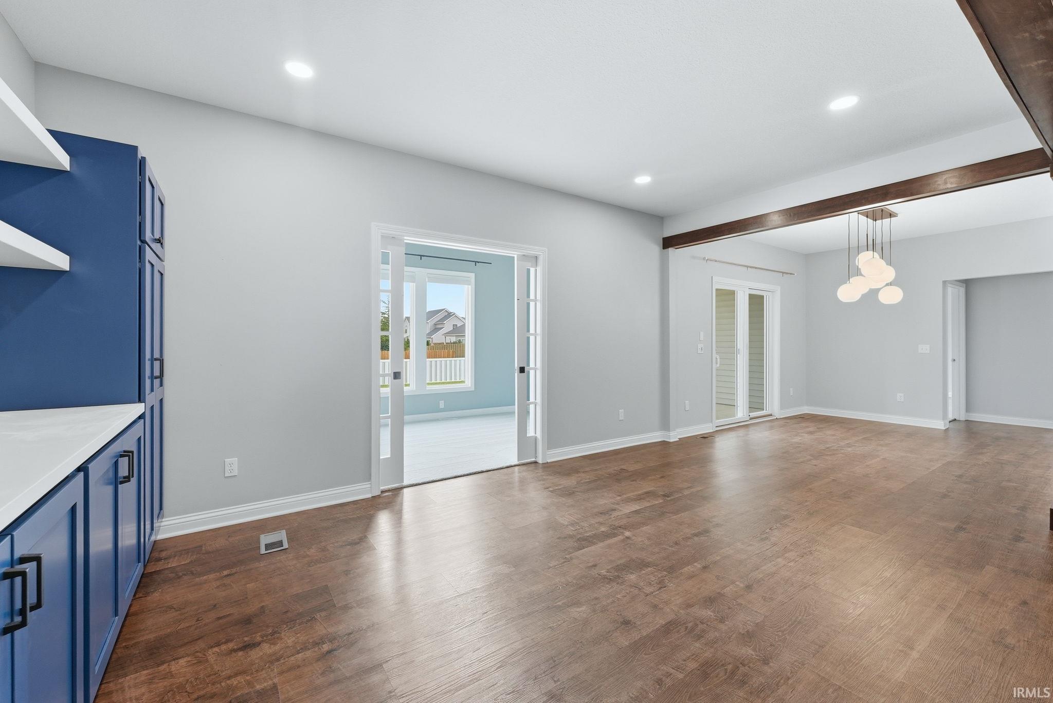 Spacious room featuring wood-finish flooring, recessed lighting, and a modern chandelier
