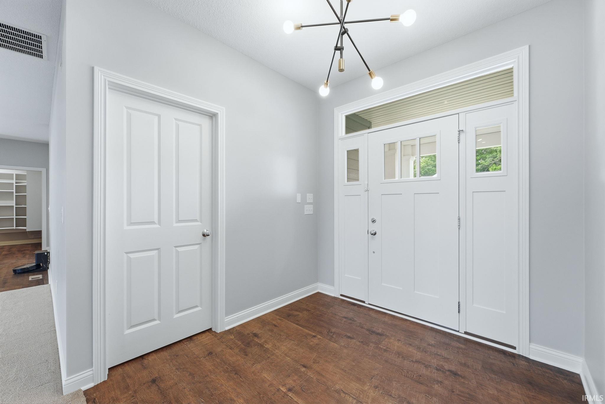 Entryway featuring a white craftsman-style door with sidelights, transom window, and wood-finish flooring