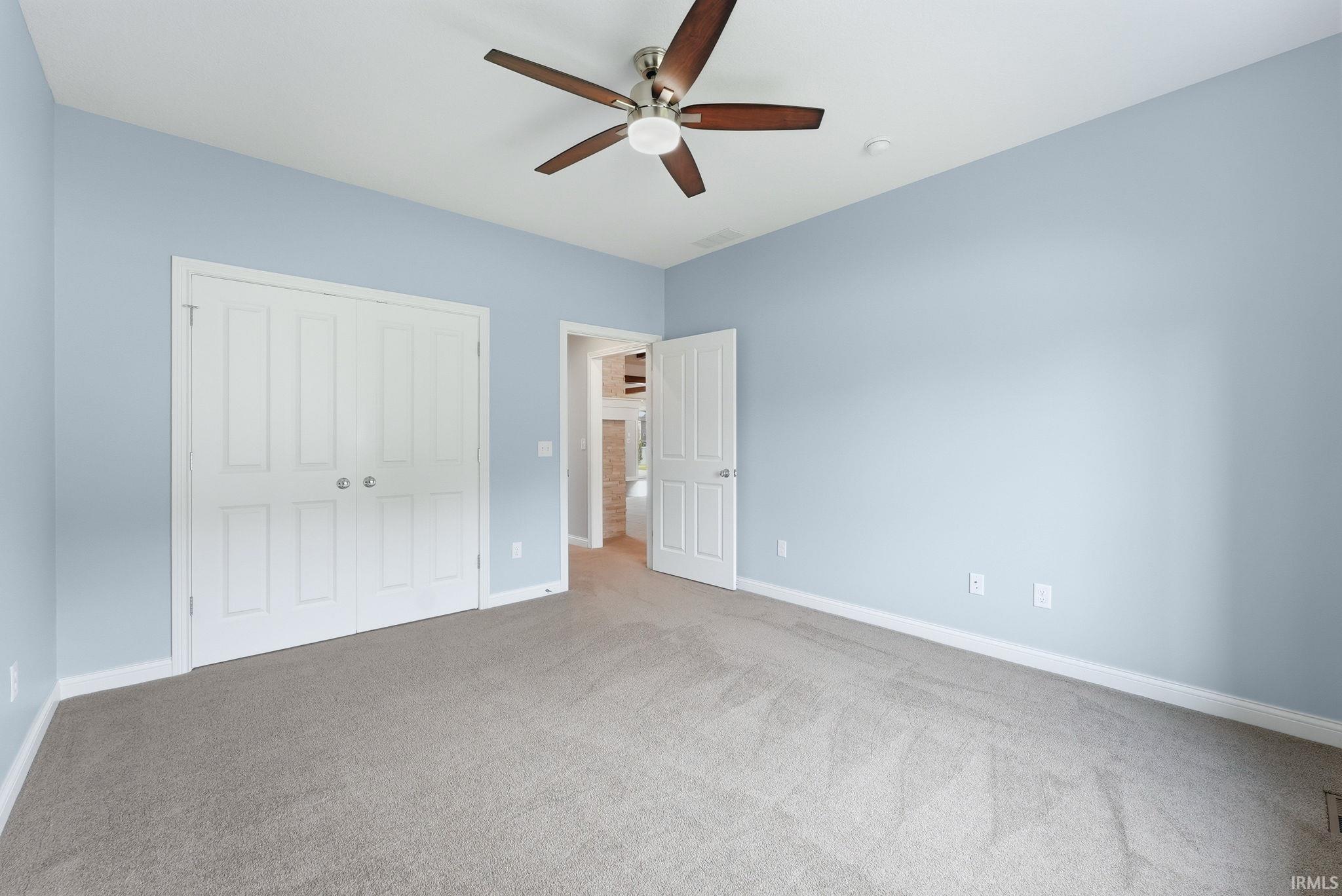 Spacious room with light blue walls and neutral-toned carpeting