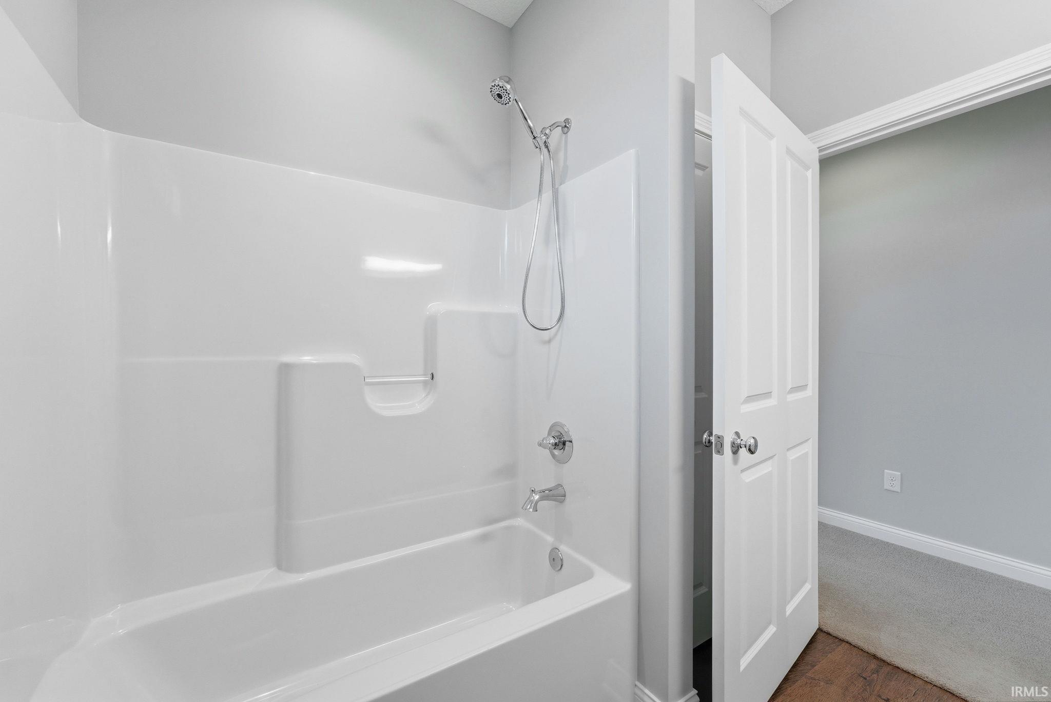 White fiberglass tub and shower combination with chrome fixtures