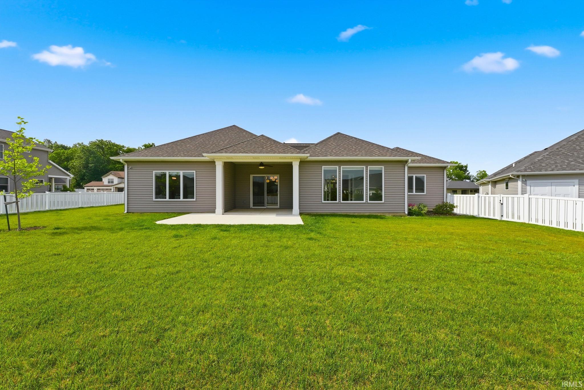 Expansive green lawn with a white privacy fence encompassing the property