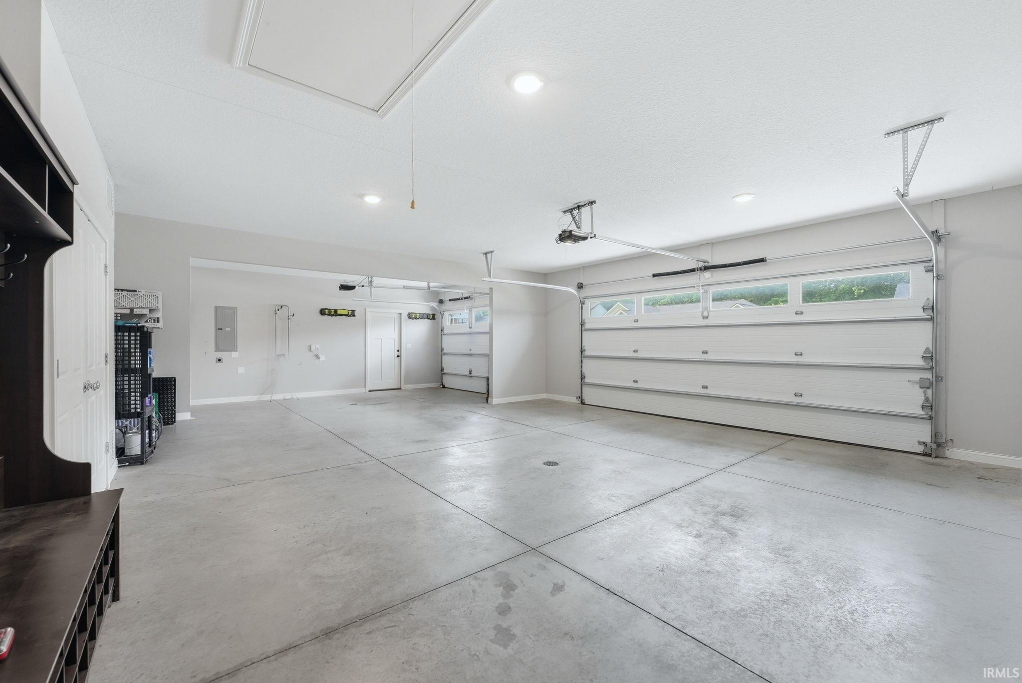 Spacious garage featuring a concrete floor, recessed lighting, and a white paneled garage door with upper-level windows