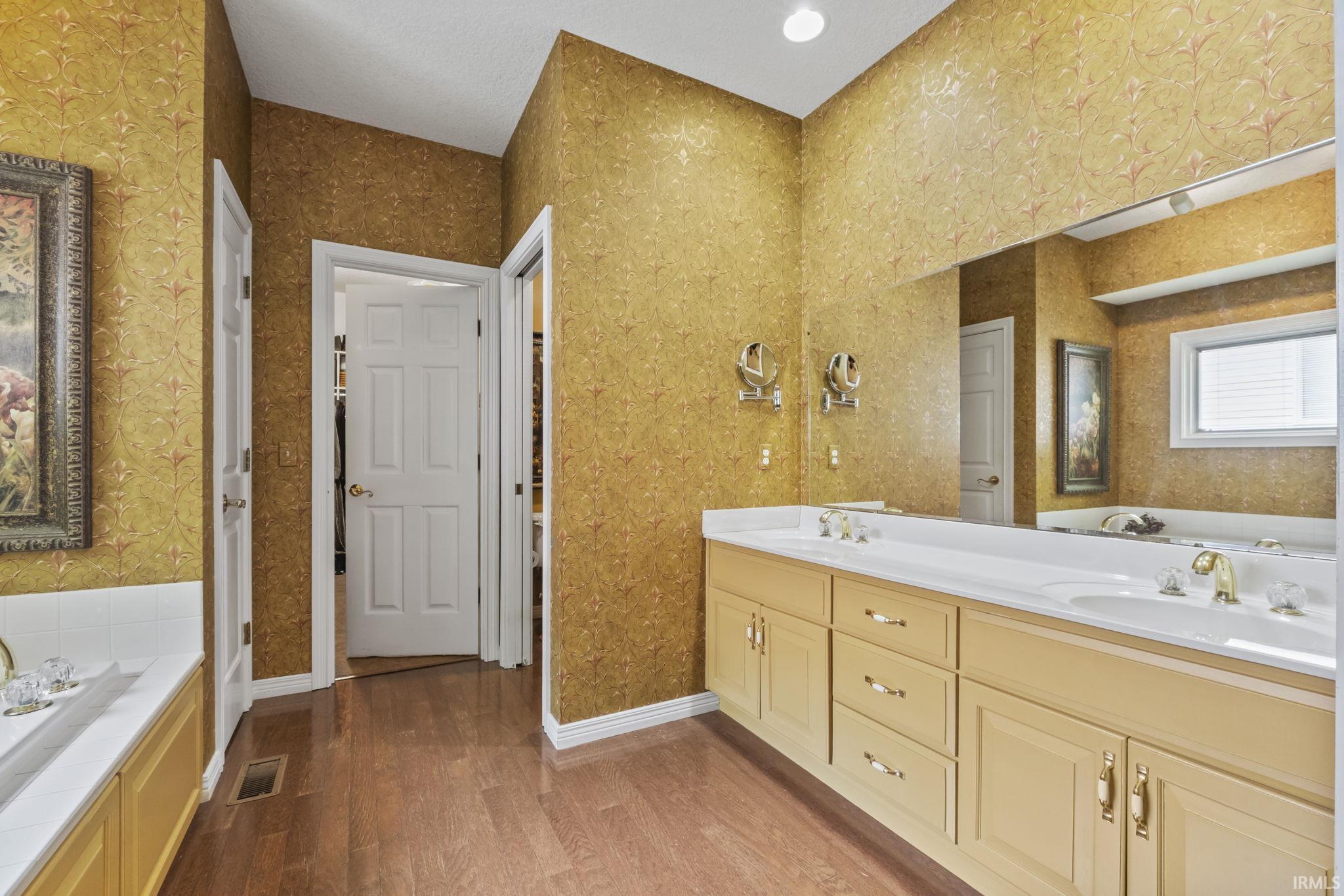 Dual sink vanity featuring light-toned cabinetry and gold-tone hardware