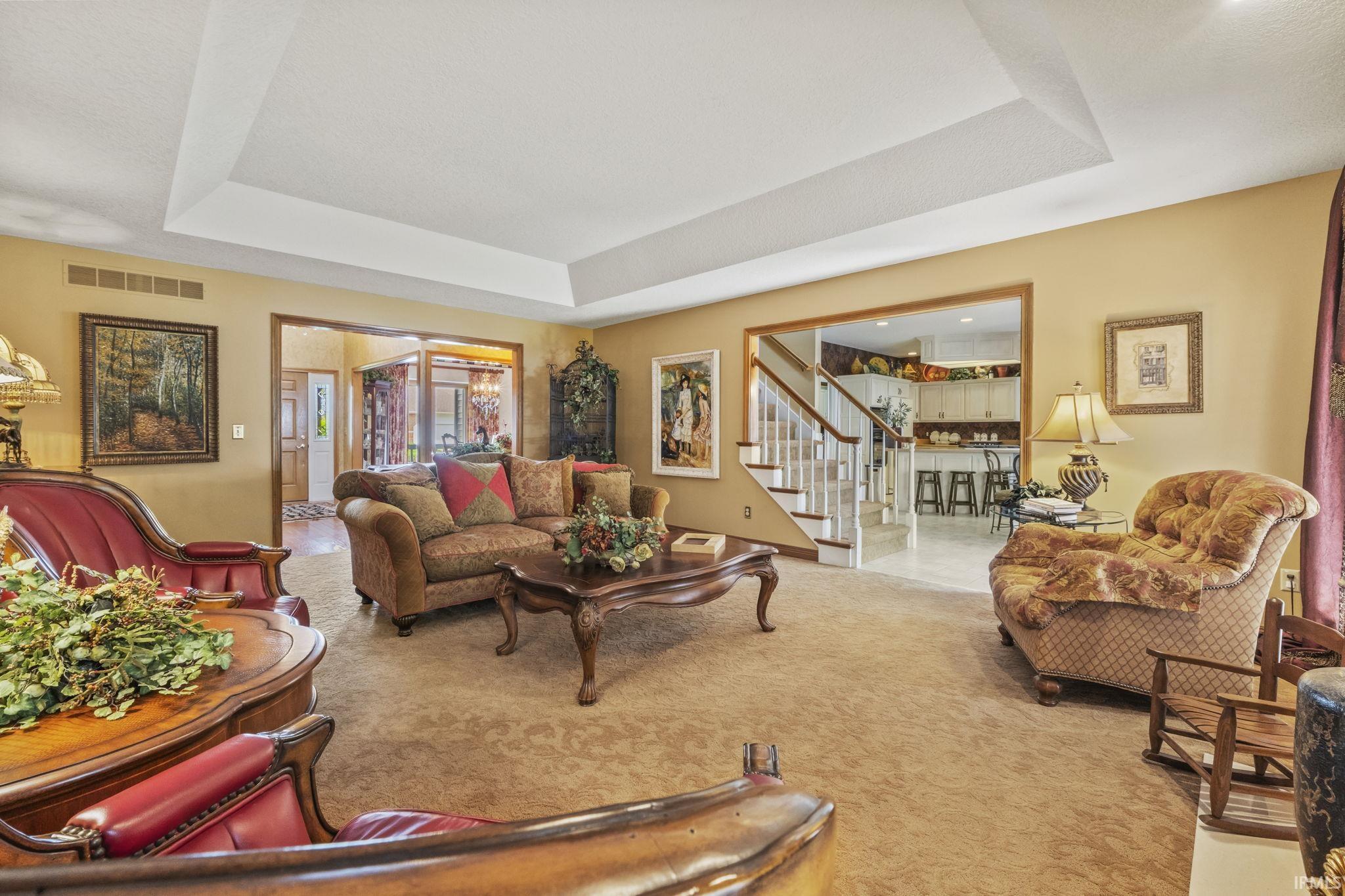 Spacious living area featuring a tray ceiling, recessed lighting, and carpet flooring