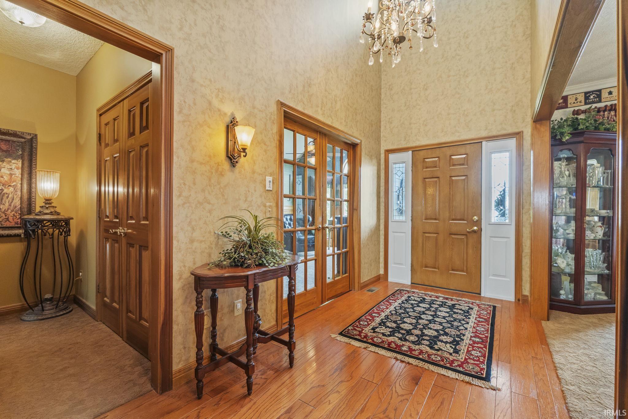 Grand entry with wood-finish flooring, a double-panel front door with sidelights, and a high ceiling featuring a chandelier