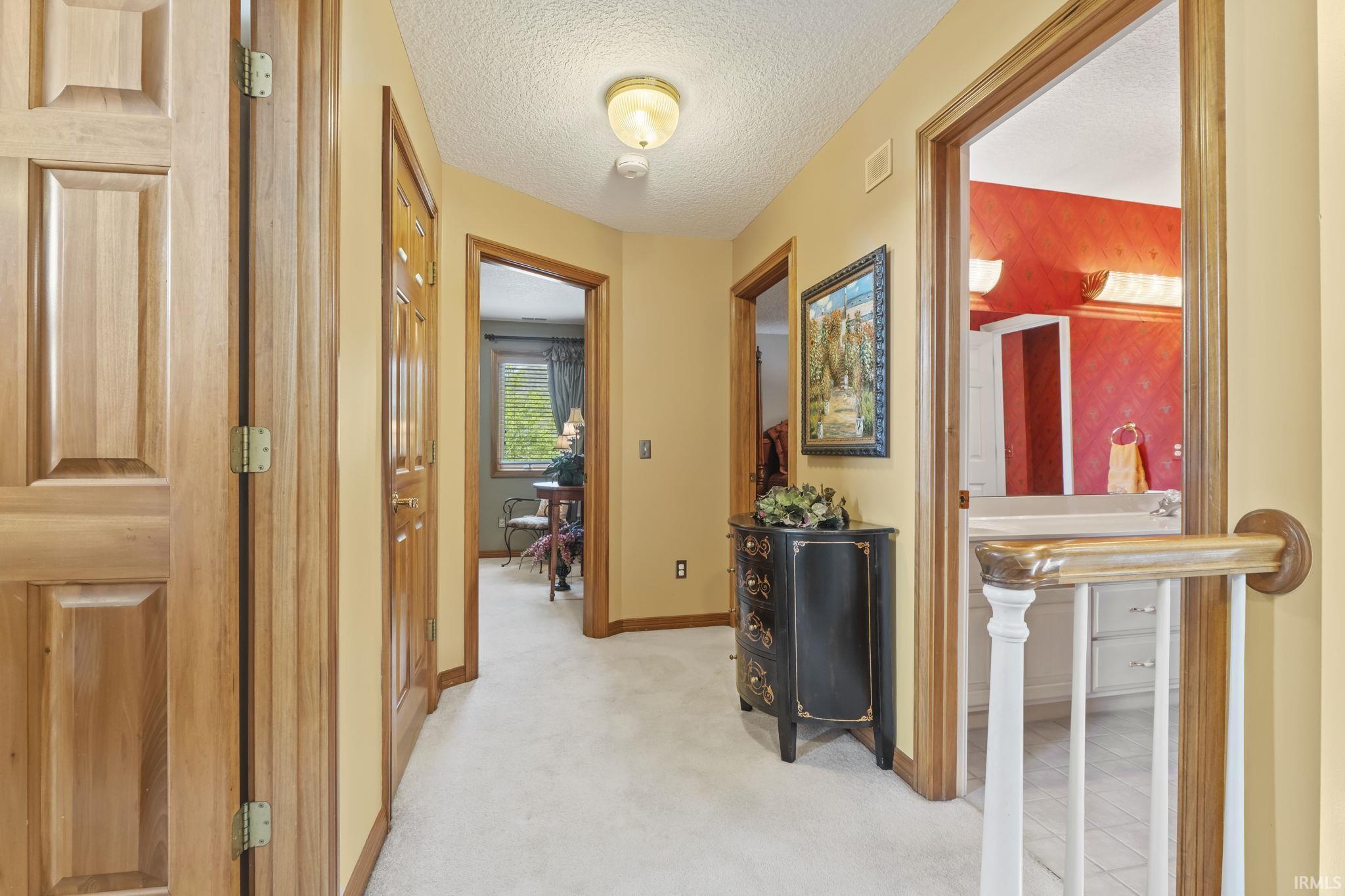 Light-colored carpeting extends through this hallway, complemented by wood-finish doors and trim