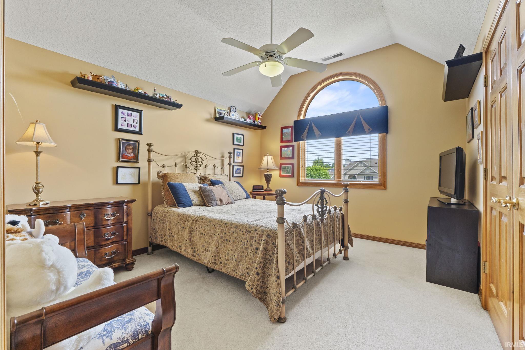 Room featuring a vaulted ceiling, light-colored carpeting, and a large arched window with horizontal blinds