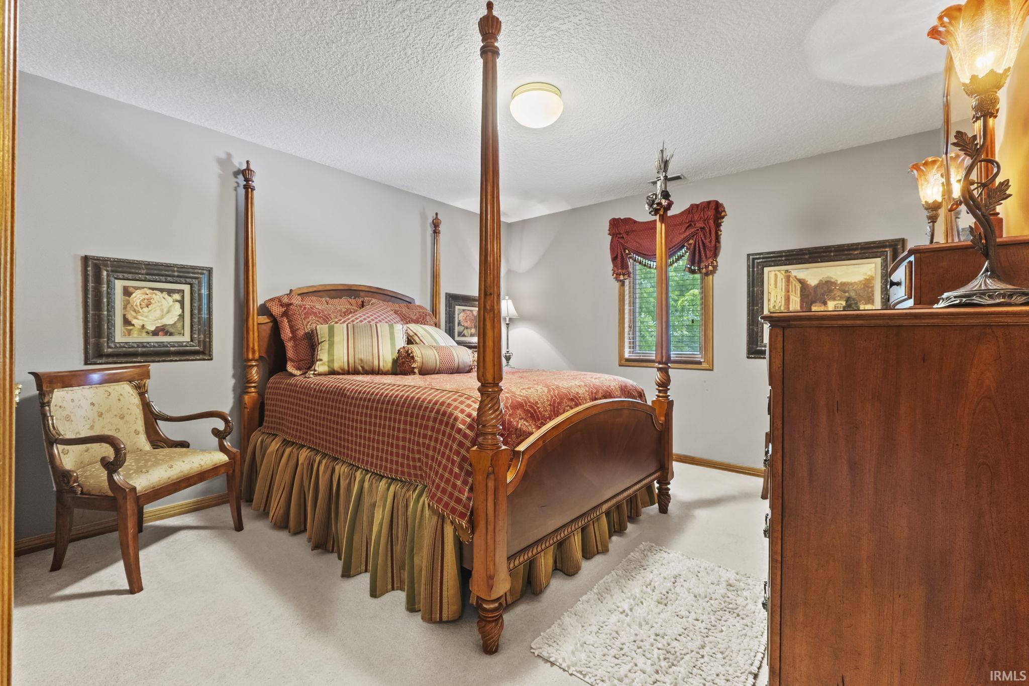 Spacious room featuring neutral painted walls, light-colored carpet flooring, a window with a valance, and a flush-mount ceiling light fixture