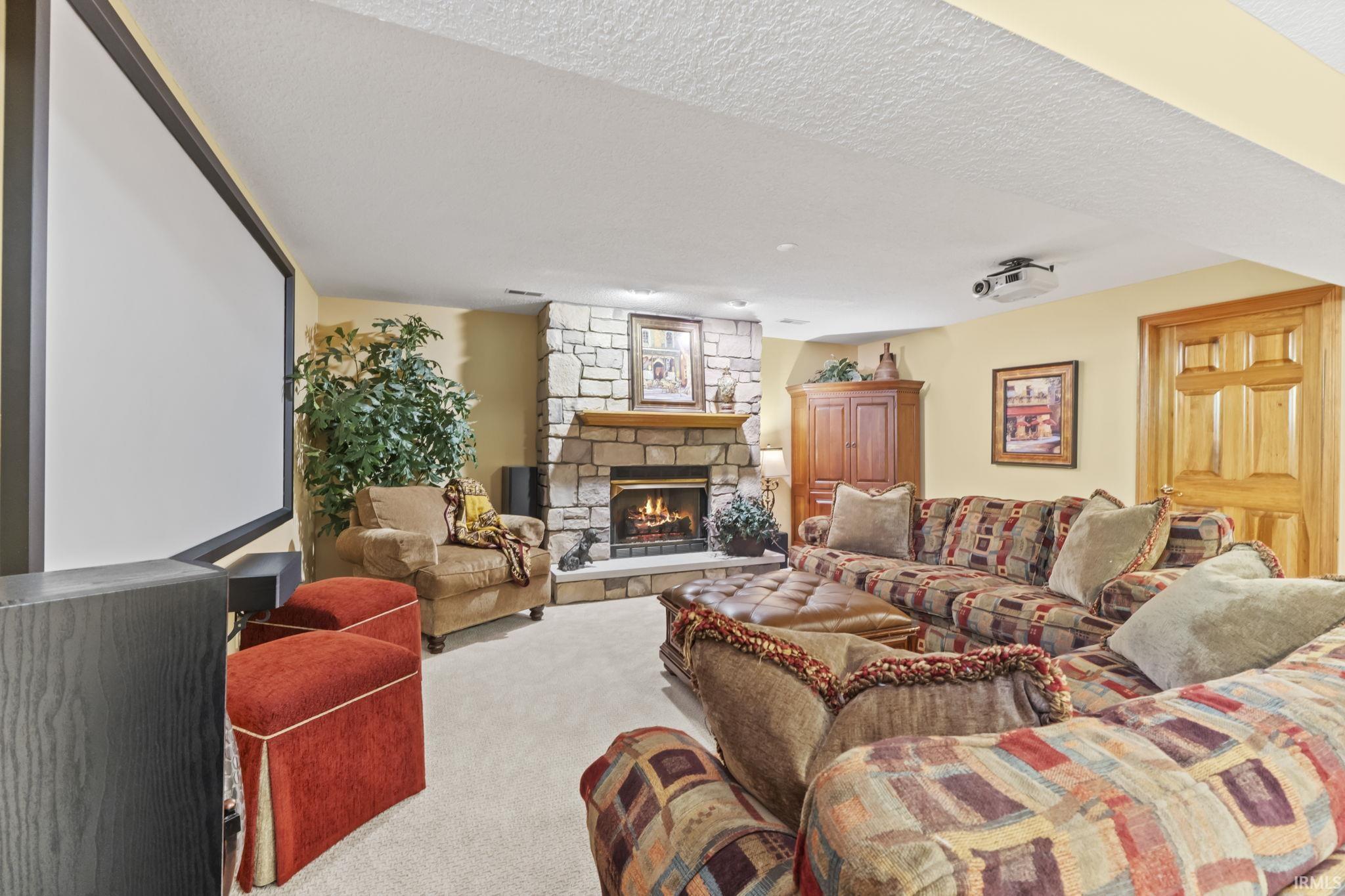 Stone-surround fireplace with a wood mantle, complemented by a large projection screen and ceiling-mounted projector