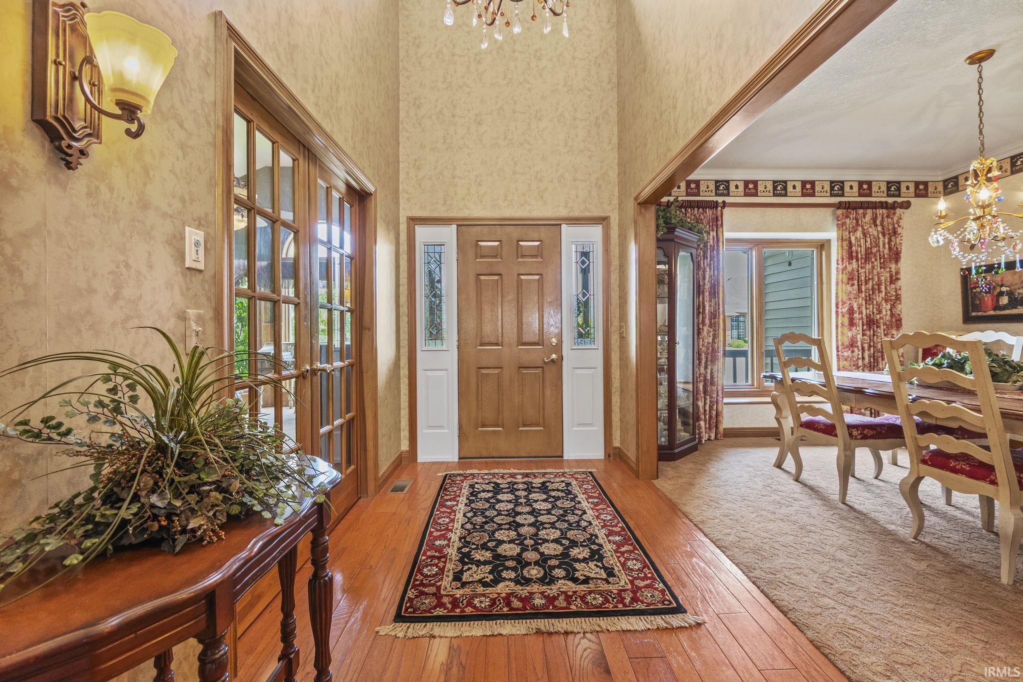 Foyer with wood-finish flooring, a wood-panel entry door with decorative glass sidelights, and a recessed ceiling