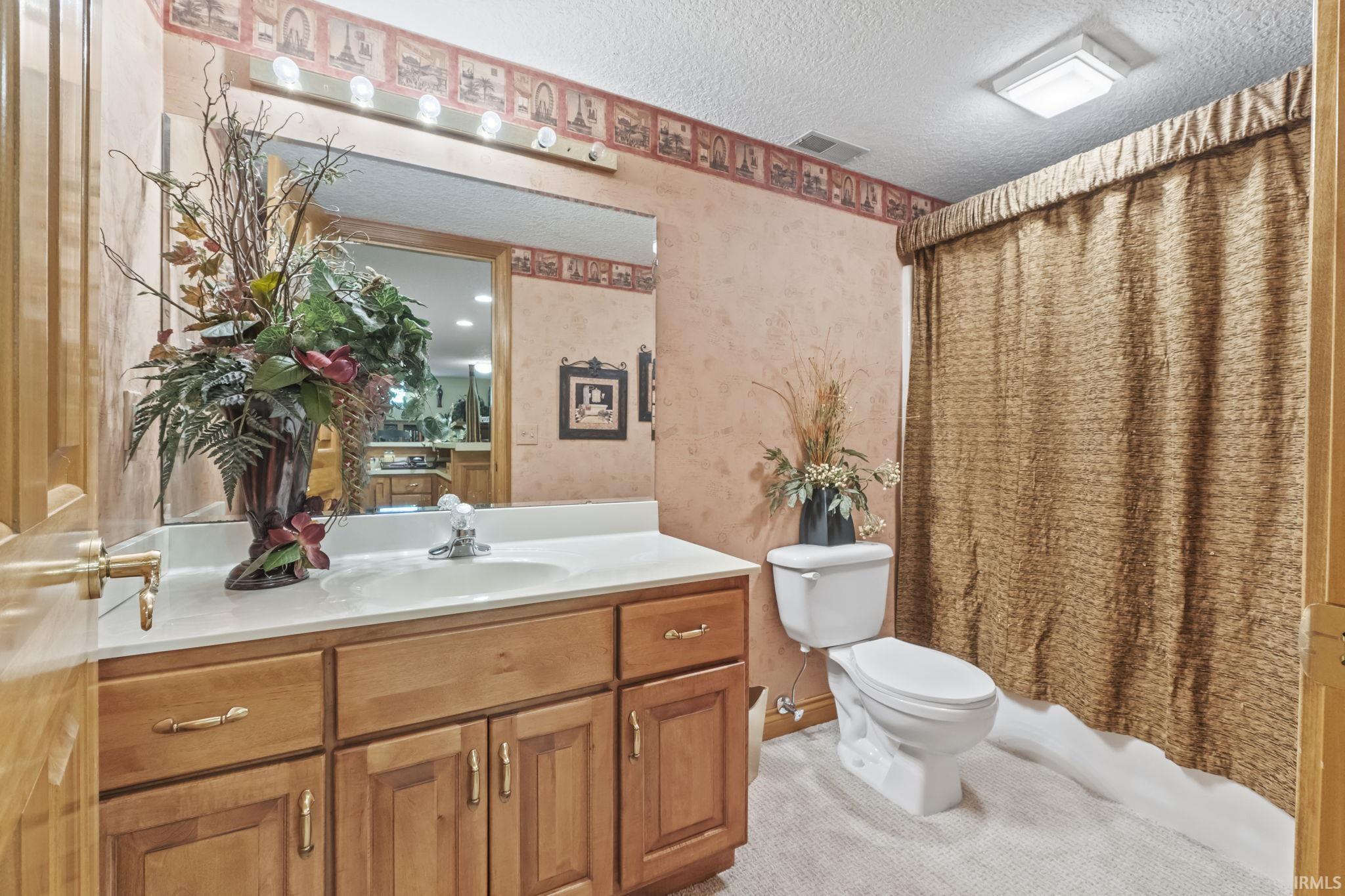Bathroom with a wood-finish vanity, integrated sink, and an expansive wall mirror