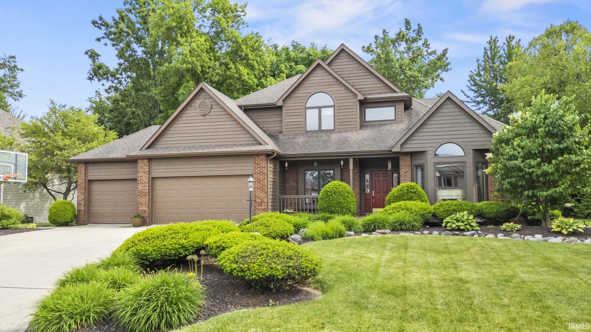 Two-story residence featuring a brown siding and brick exterior with multiple gables