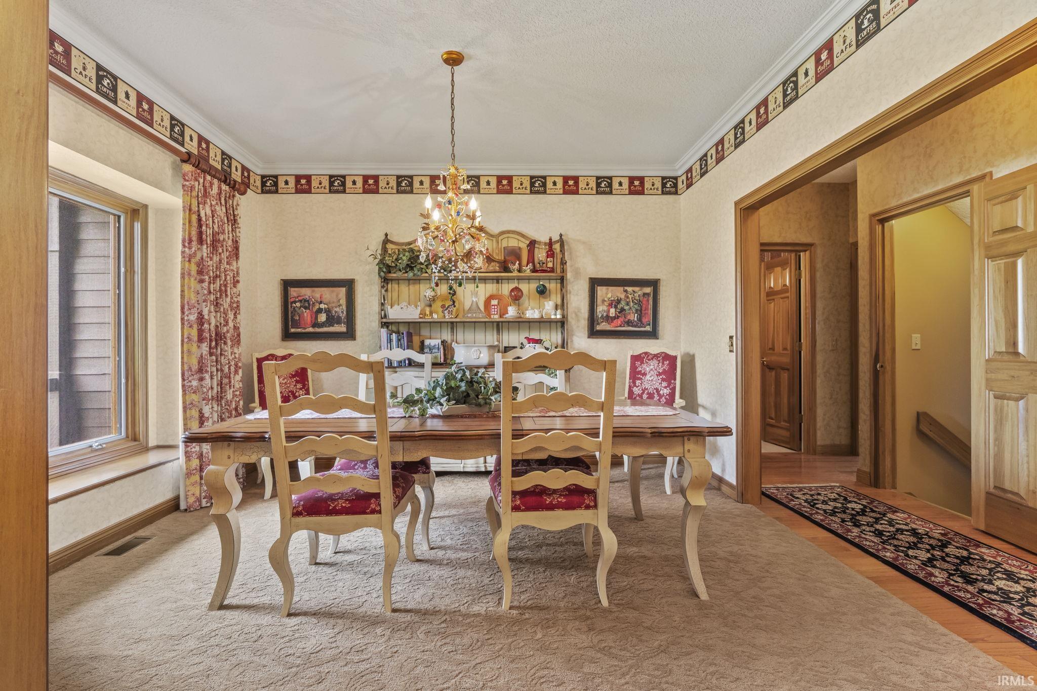 Formal dining area featuring a decorative chandelier, coved ceiling with border, and a large window