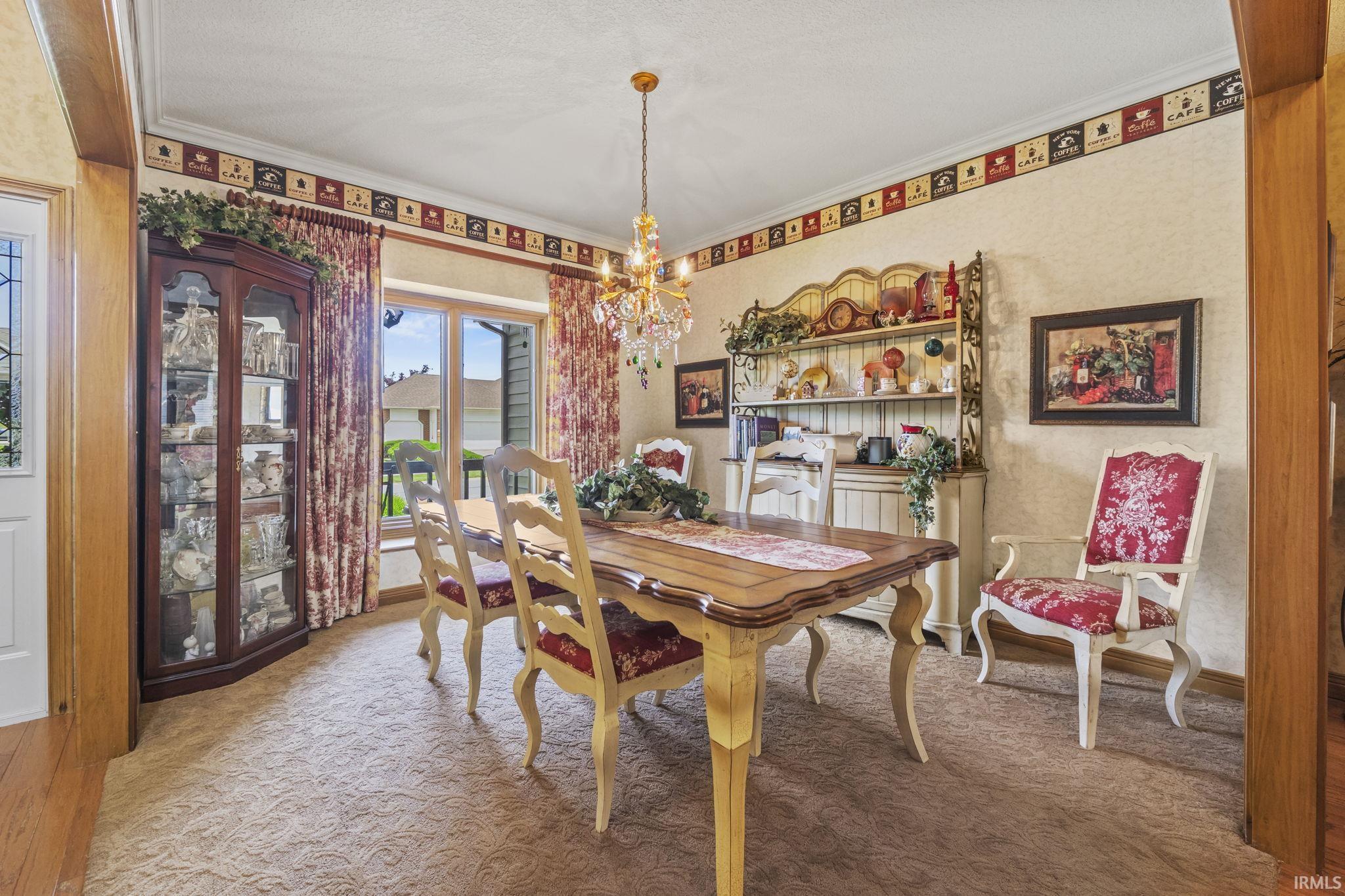 Formal dining area featuring a decorative chandelier, patterned carpet flooring, and a large window with privacy curtains