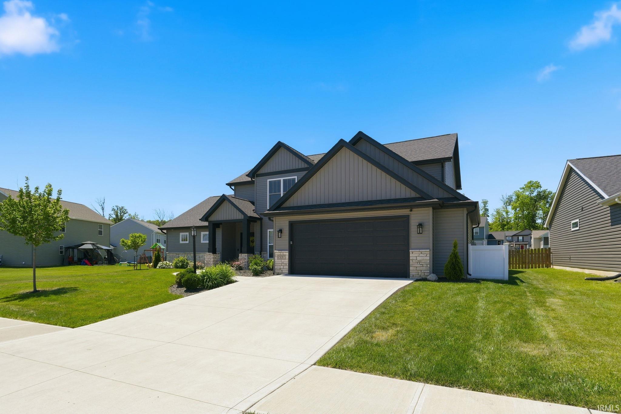 Contemporary exterior featuring gray siding, stone accents, a dark roof, and a two-car garage