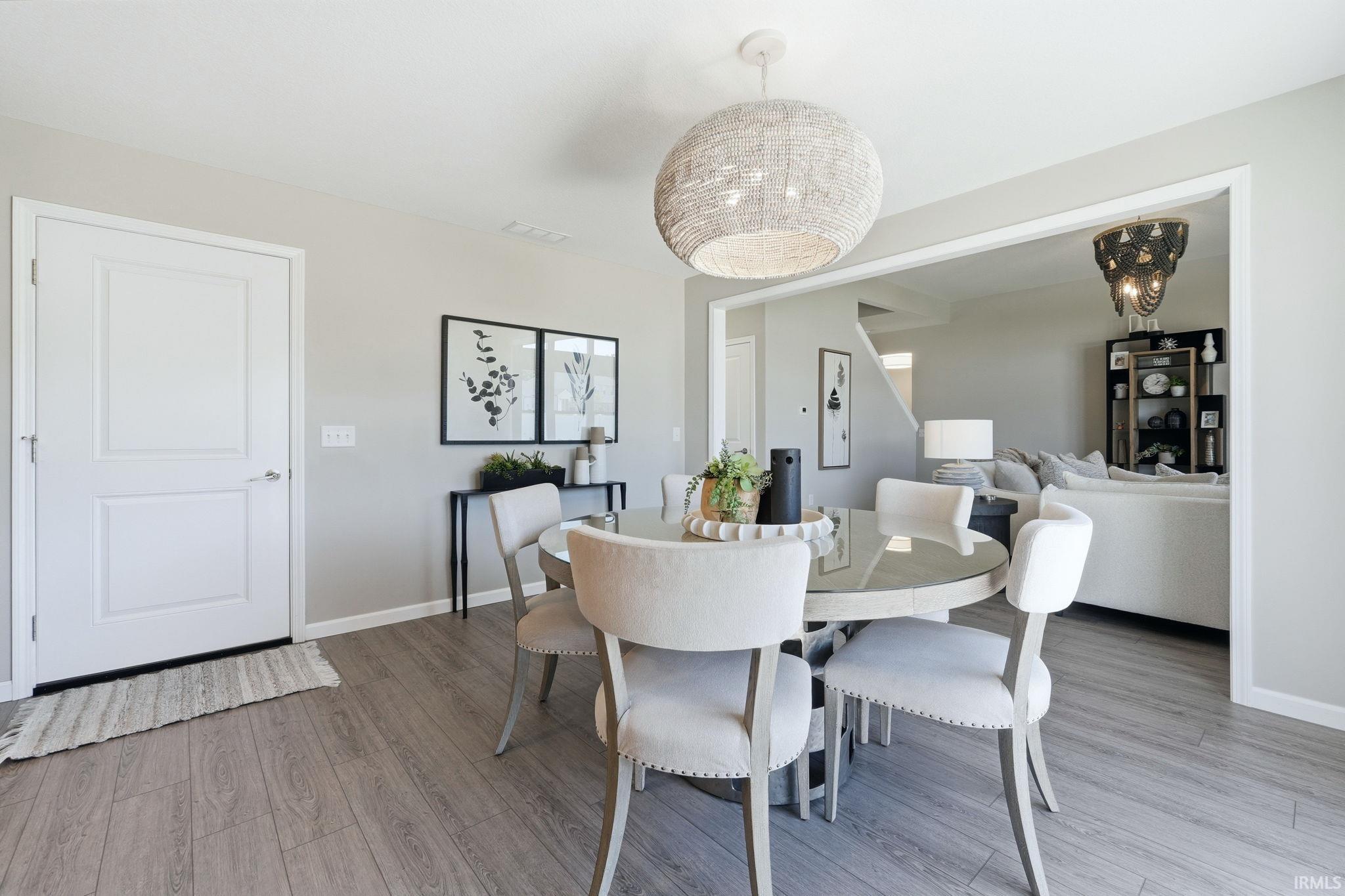 Dining area featuring wood-finish flooring, a round glass-top table, and a woven pendant light fixture