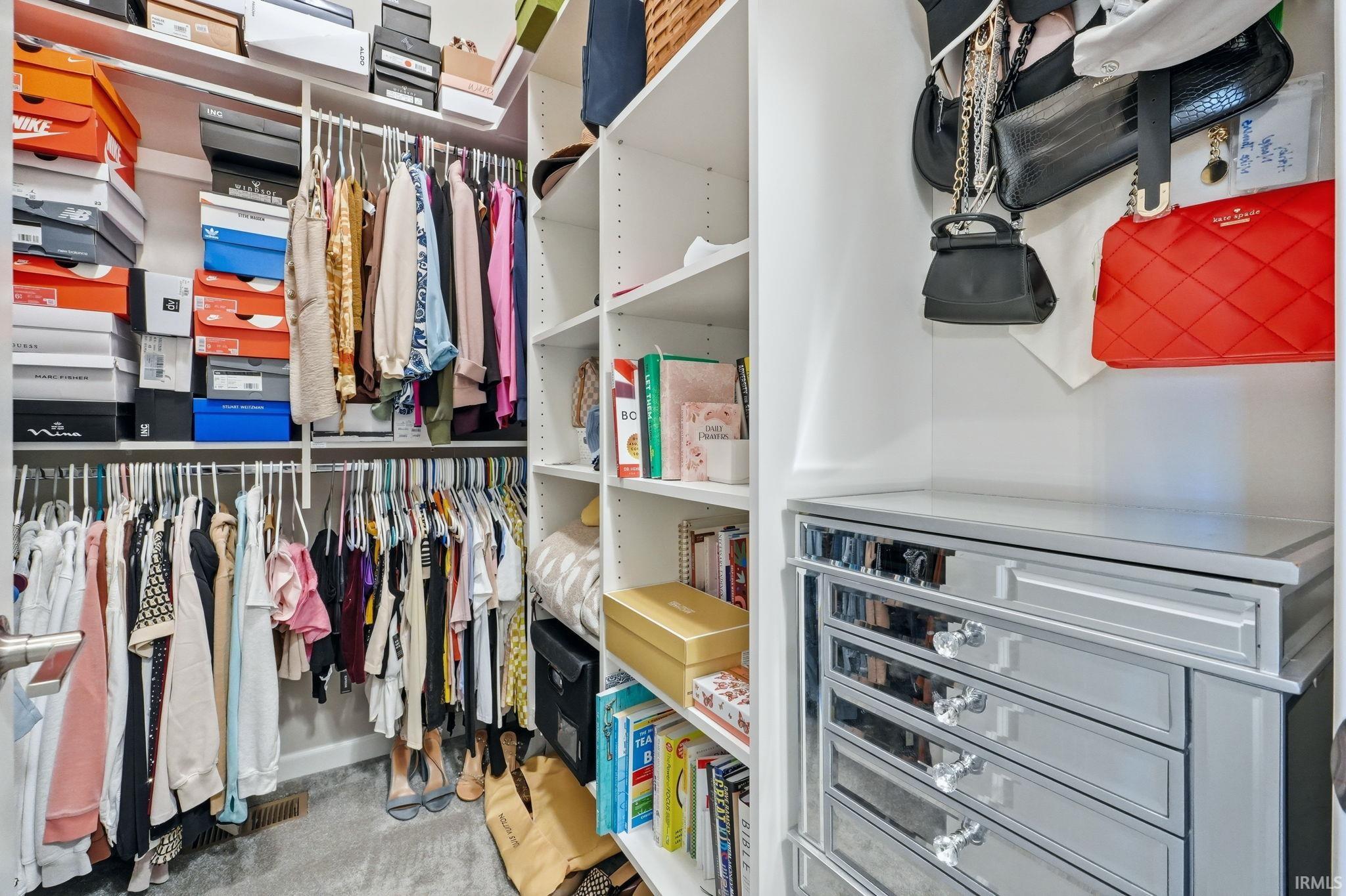 Custom closet system featuring built-in shelving, multiple hanging rods, and a mirrored drawer chest with decorative pulls