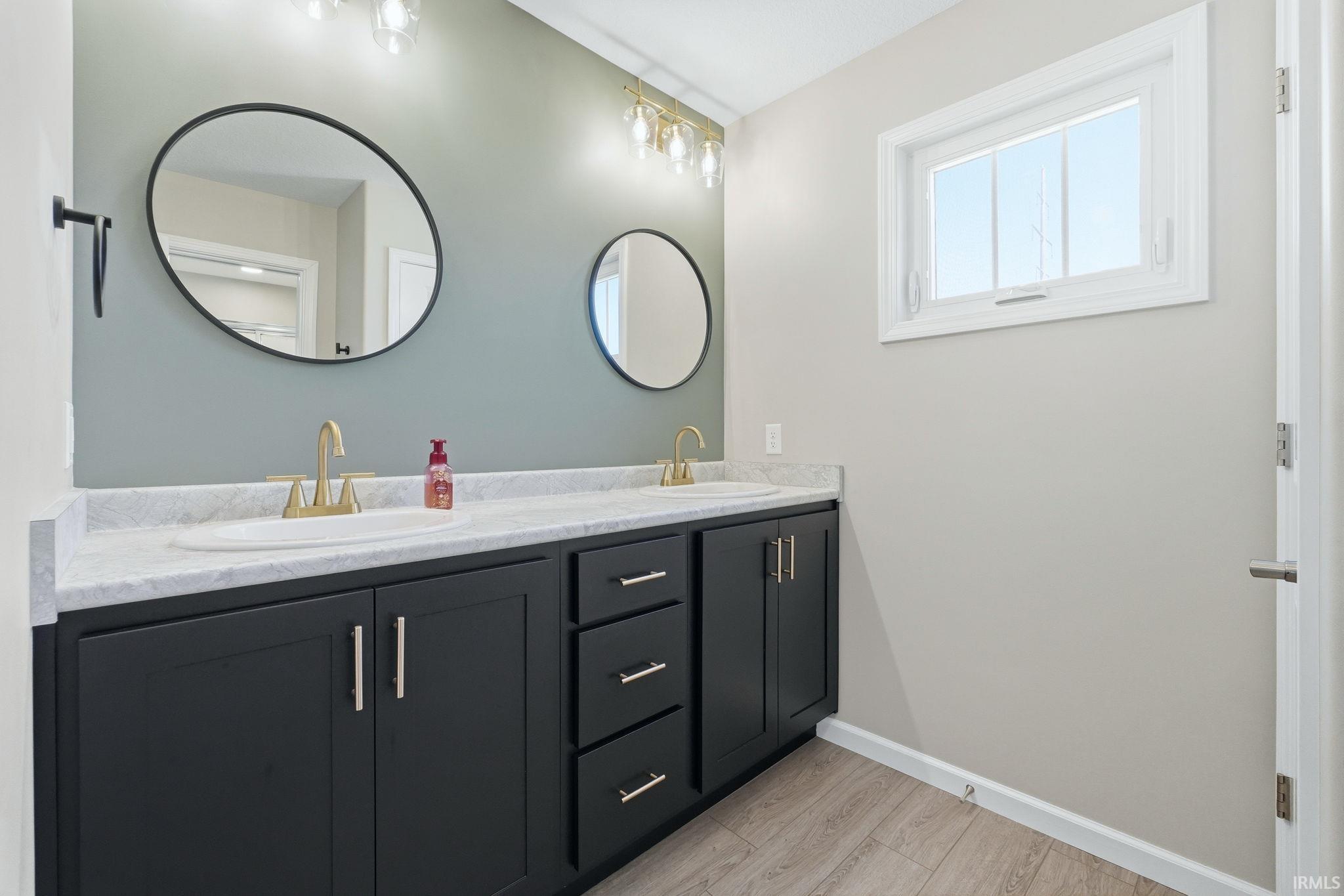 Dual vanity with black cabinetry, white countertops, and gold-finish faucets