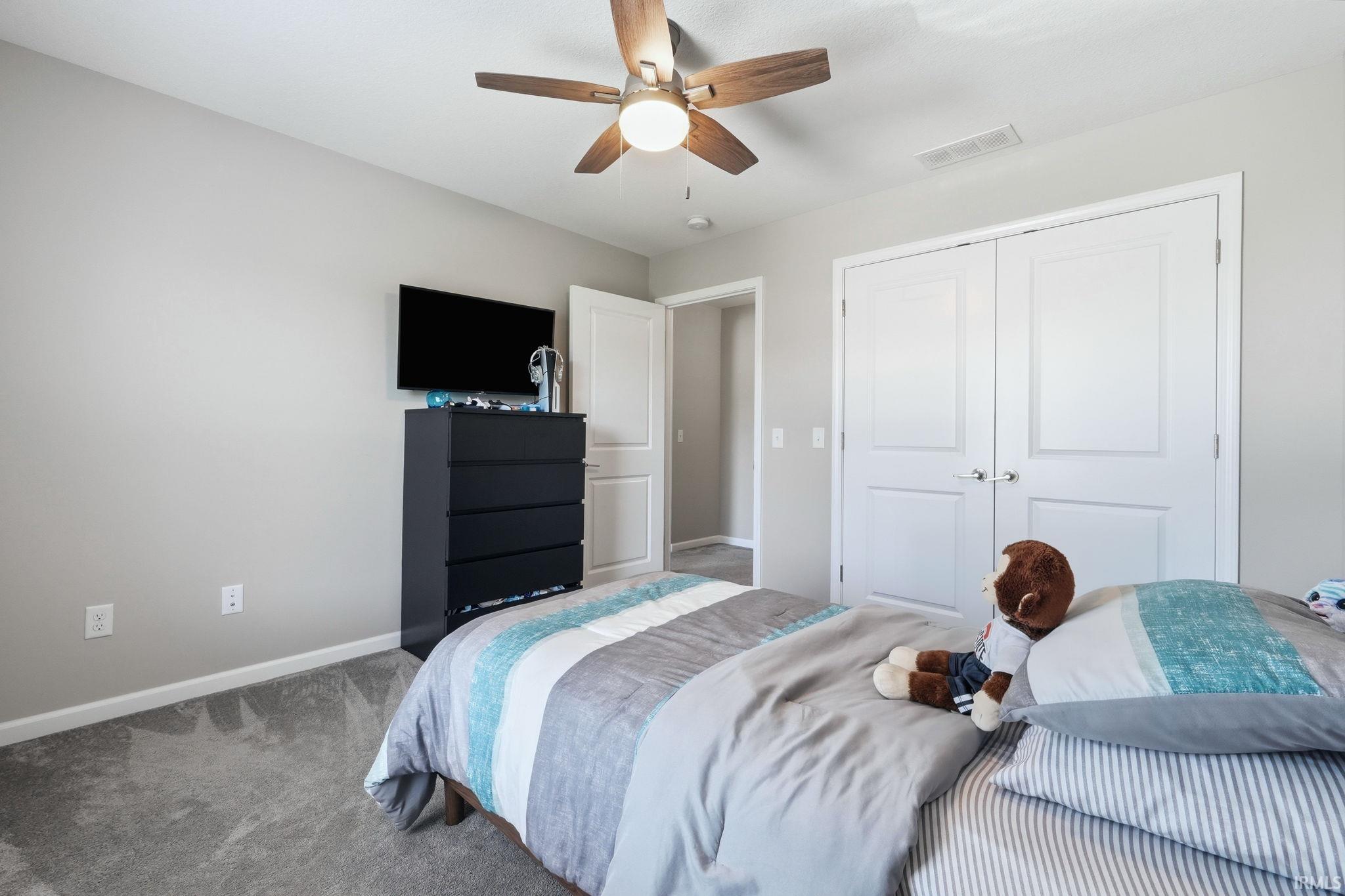 Carpeted room with a ceiling fan, light gray walls, white trim, and a bi-fold closet door