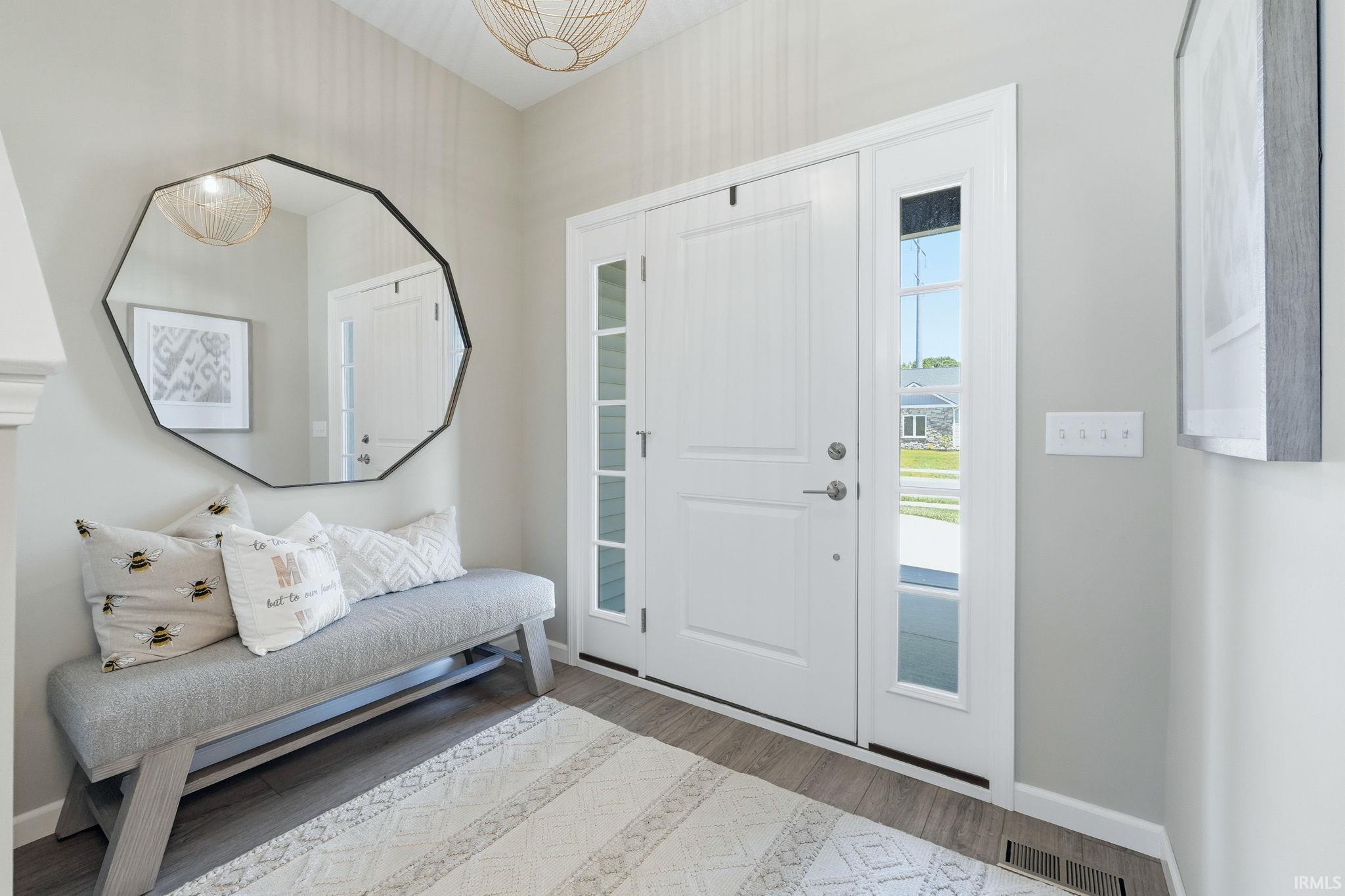Inviting entryway featuring a white paneled front door with sidelights, wood-finish flooring, and a contemporary ceiling light fixture