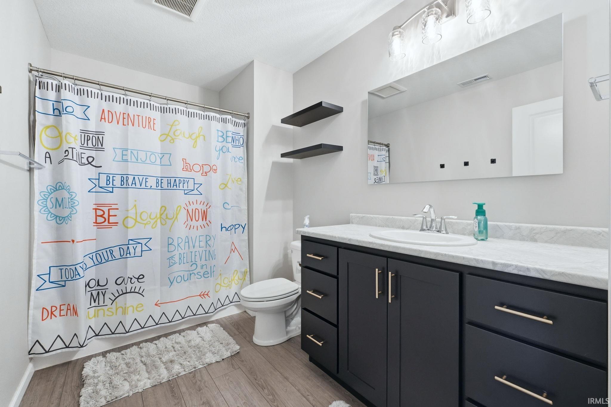 Bathroom featuring a single vanity with dark cabinetry, gold-finish hardware, and a white countertop with an integrated sink