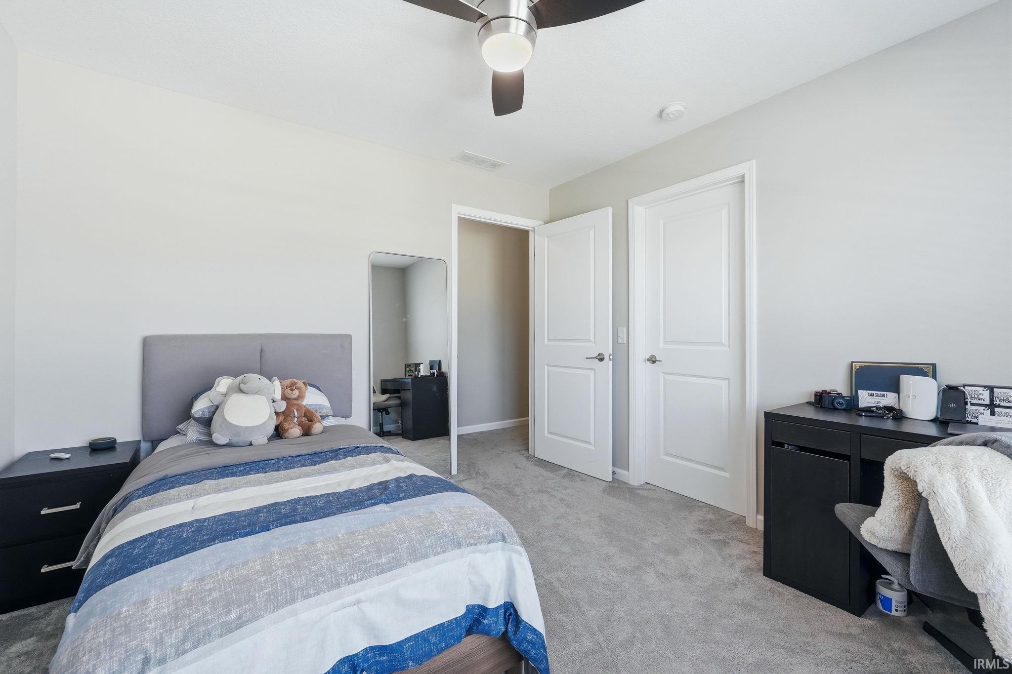 Carpeted room featuring a ceiling fan with integrated lighting, two panel doors, and neutral wall tones