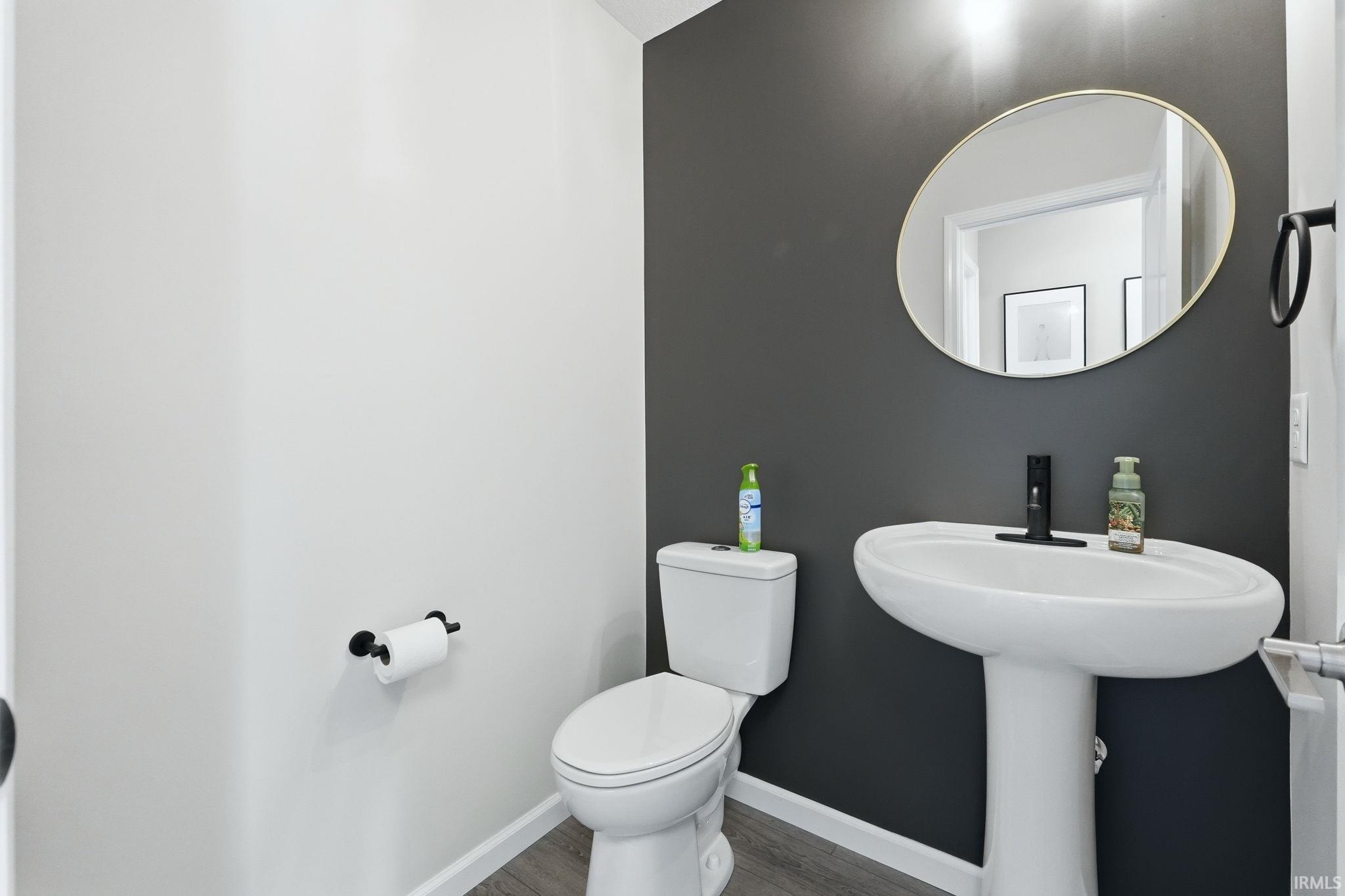 Powder room featuring a pedestal sink with a matte black faucet, a gold-framed oval mirror, and a two-tone wall treatment