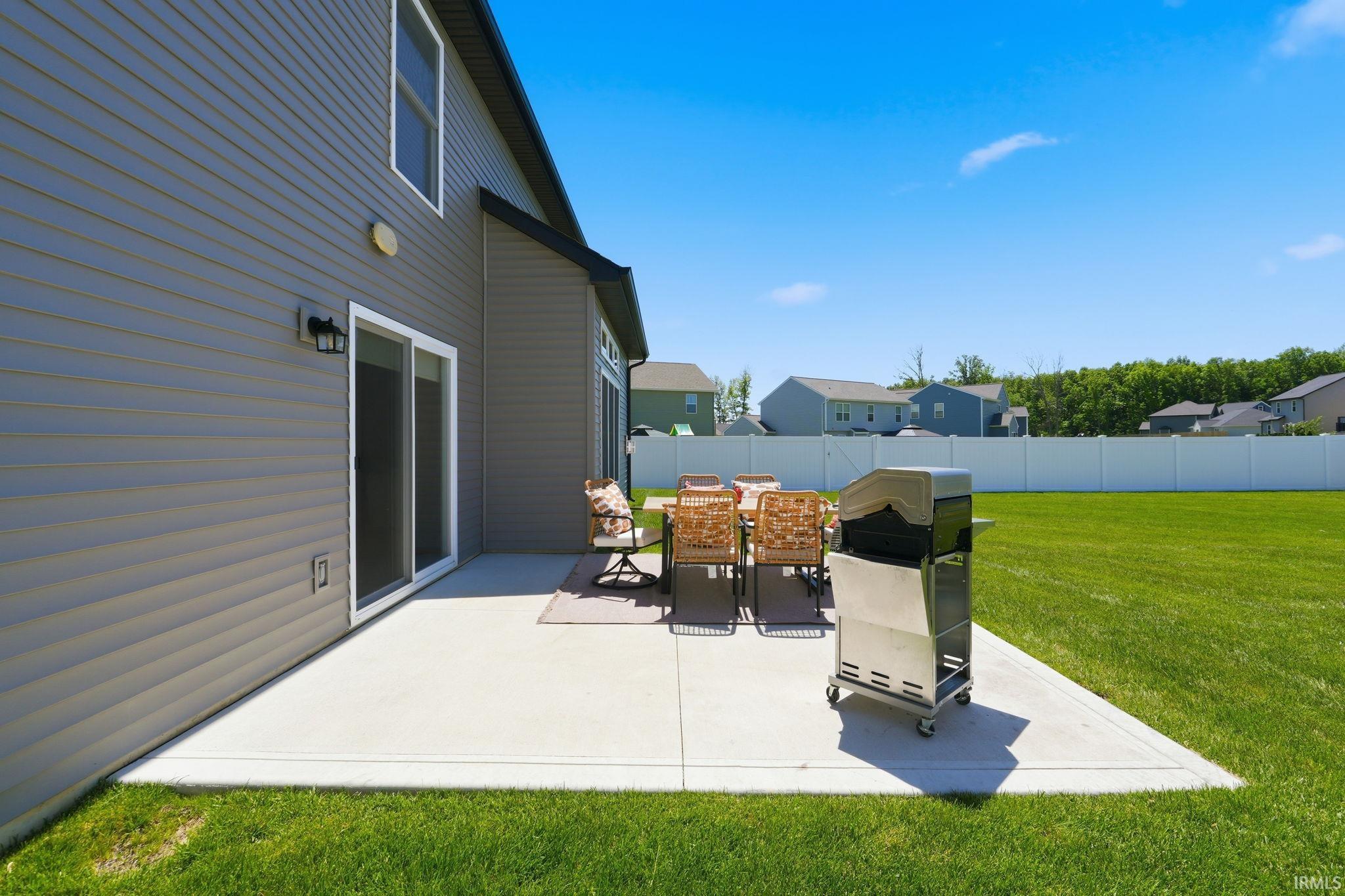 Expansive concrete patio with sliding glass door access to the interior