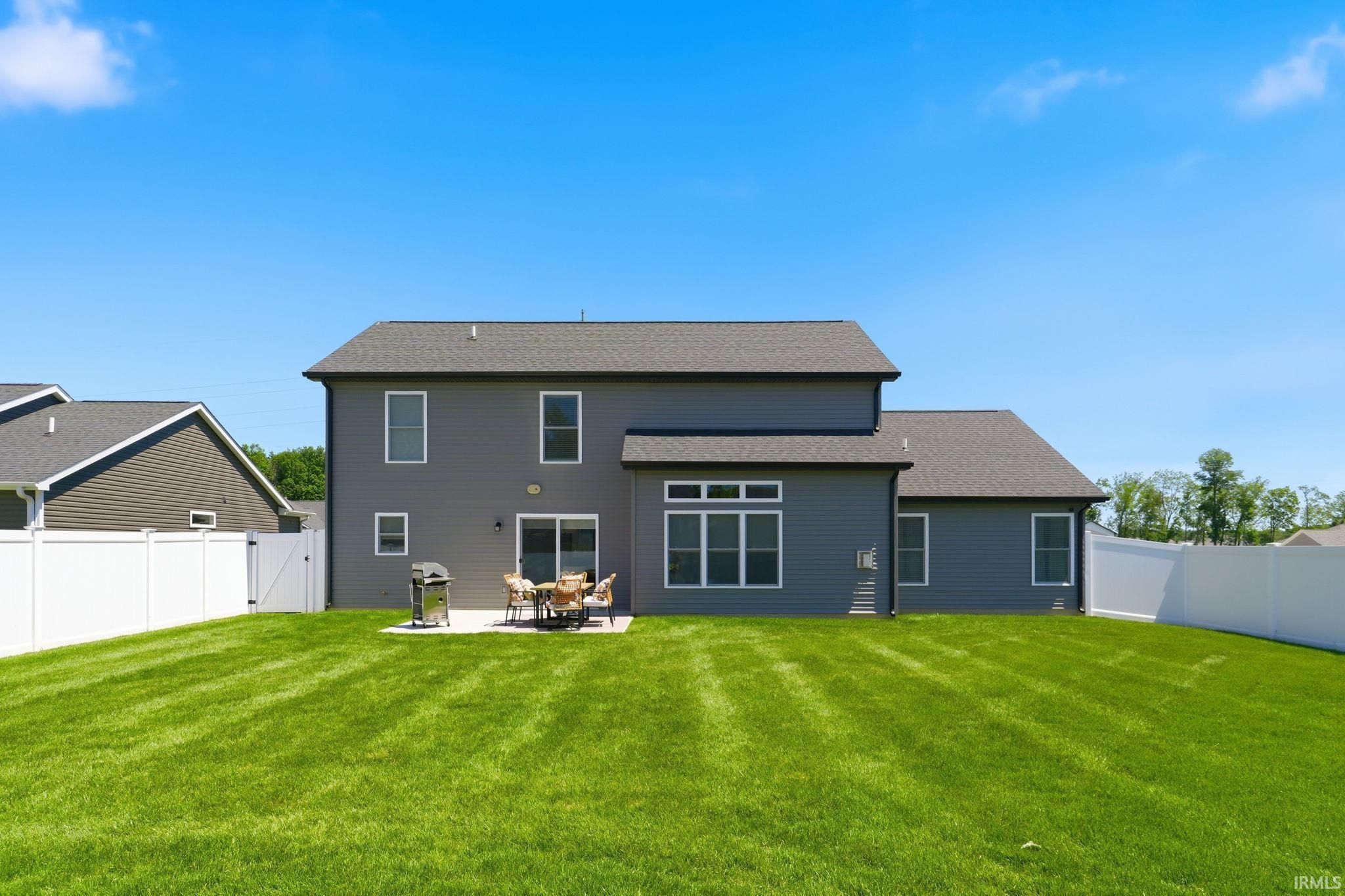 Expansive green lawn with a white privacy fence