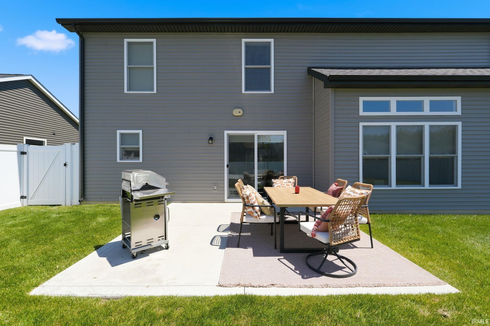 Rear exterior featuring gray horizontal siding, a concrete patio, and a sliding glass door