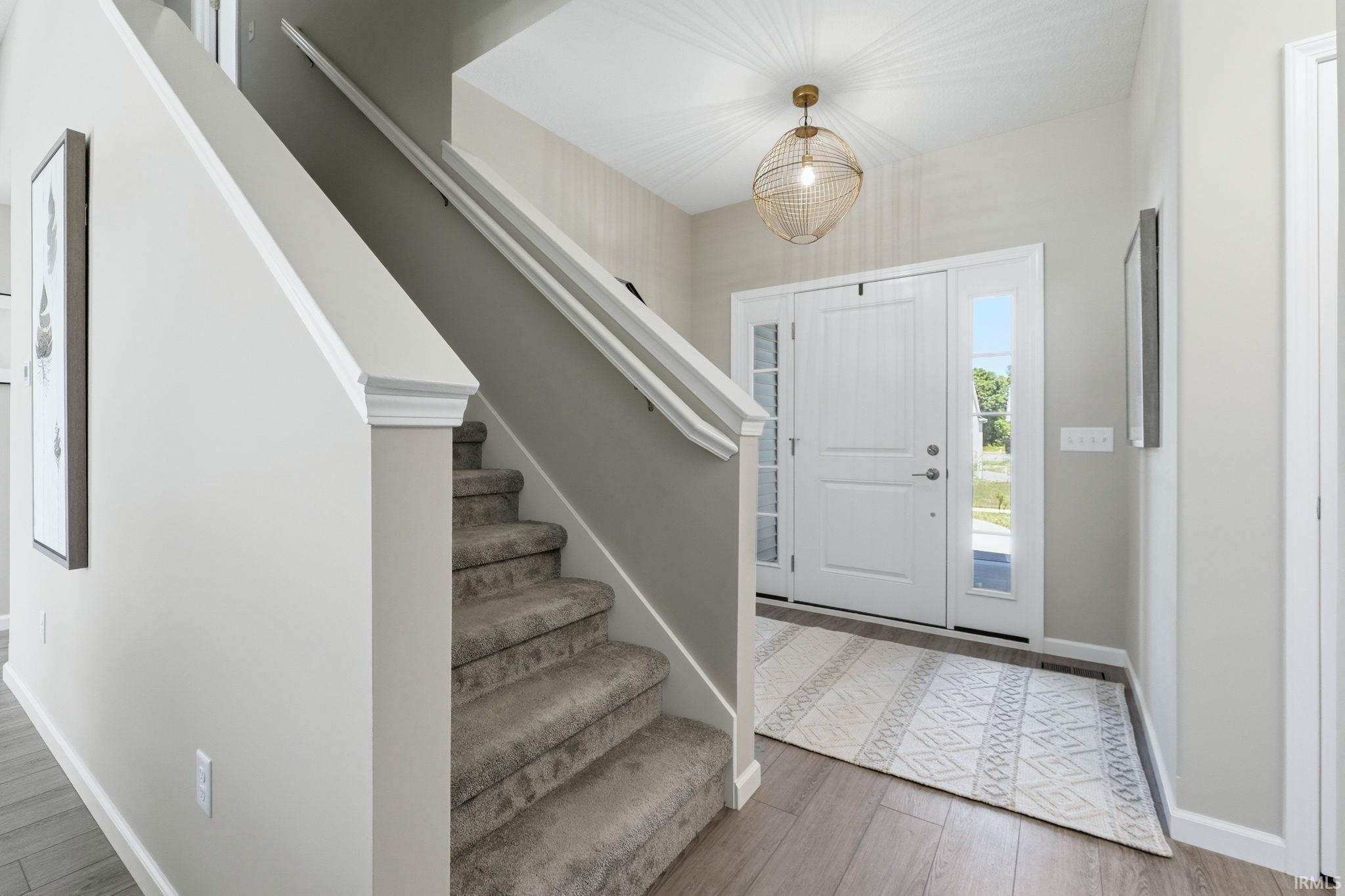 Bright entryway featuring wood-finish flooring and a carpeted staircase