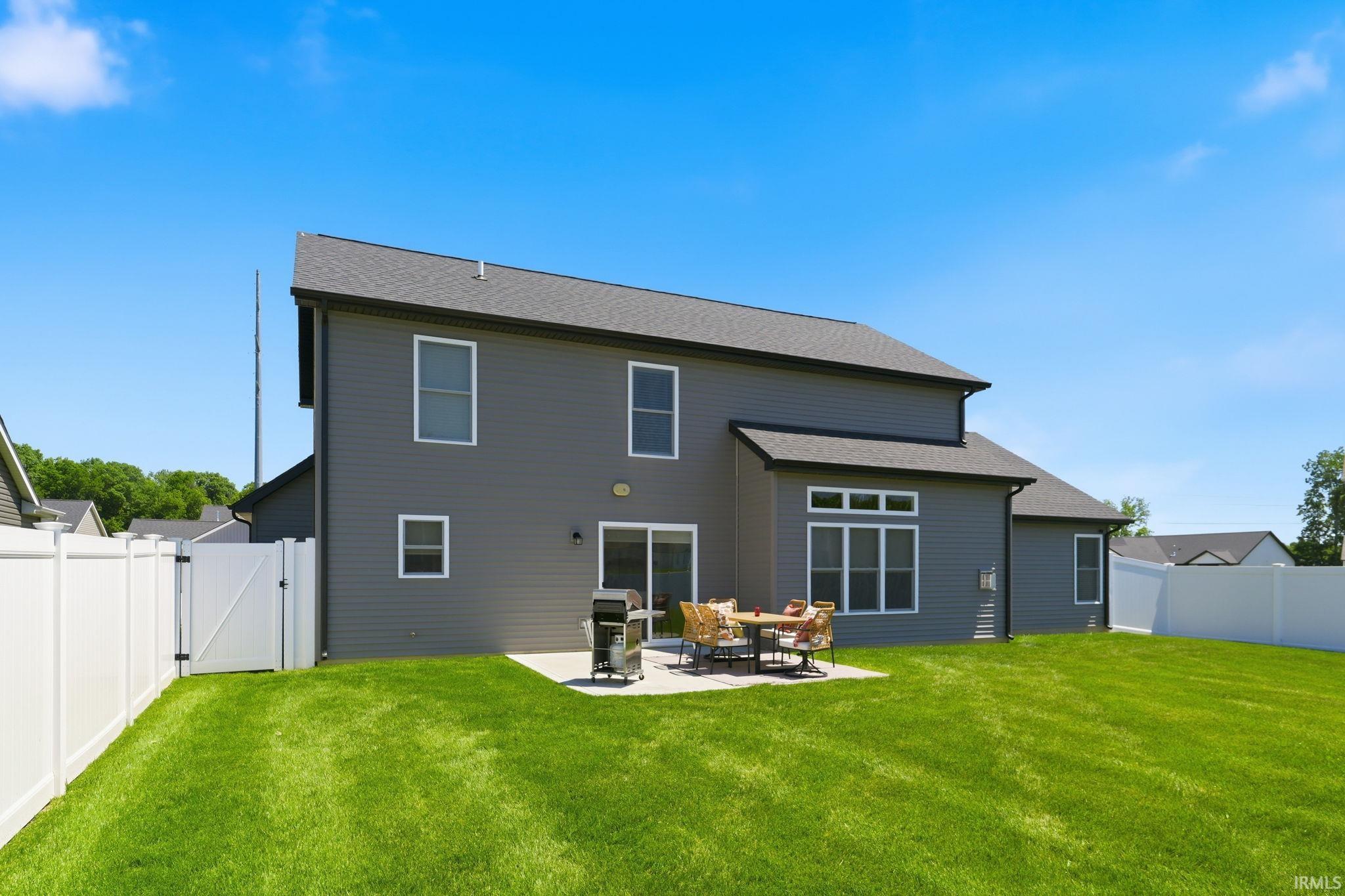 Spacious backyard featuring a large concrete patio and vibrant green lawn