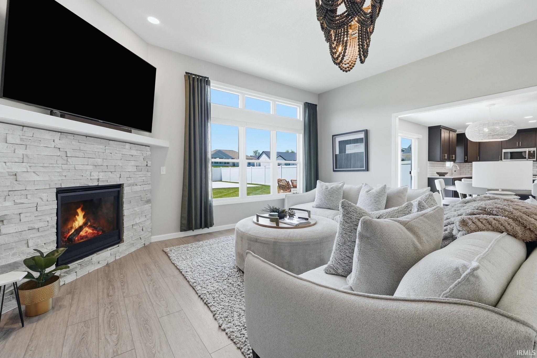Living space featuring a stacked stone fireplace with a floating mantel, wood-finish flooring, and expansive windows