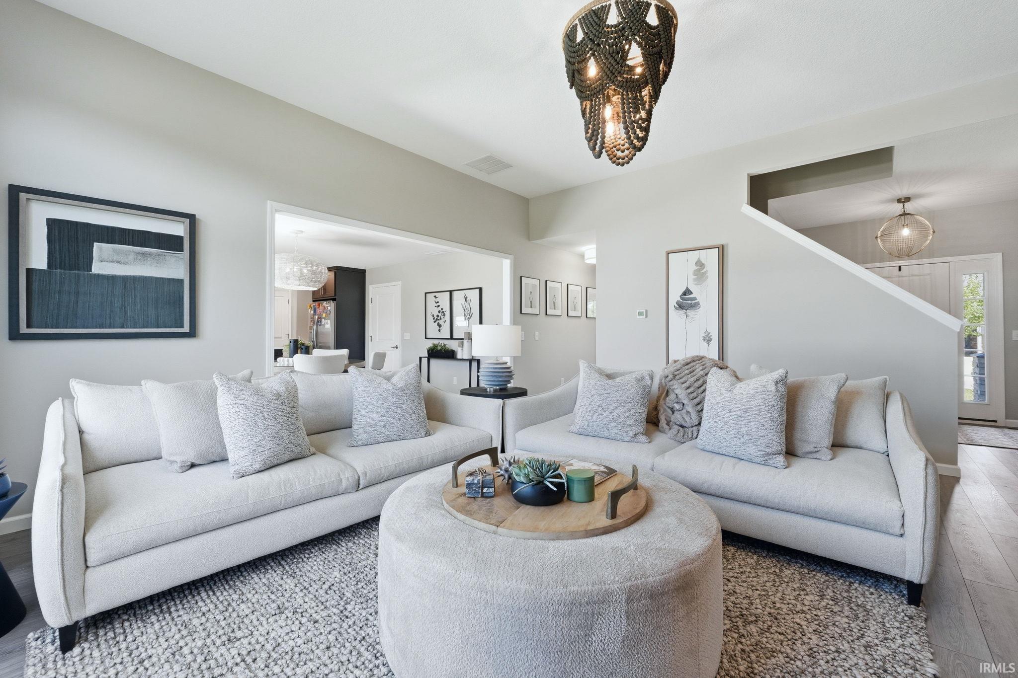 Bright living area featuring wood-finish flooring, a contemporary chandelier, and an open concept layout