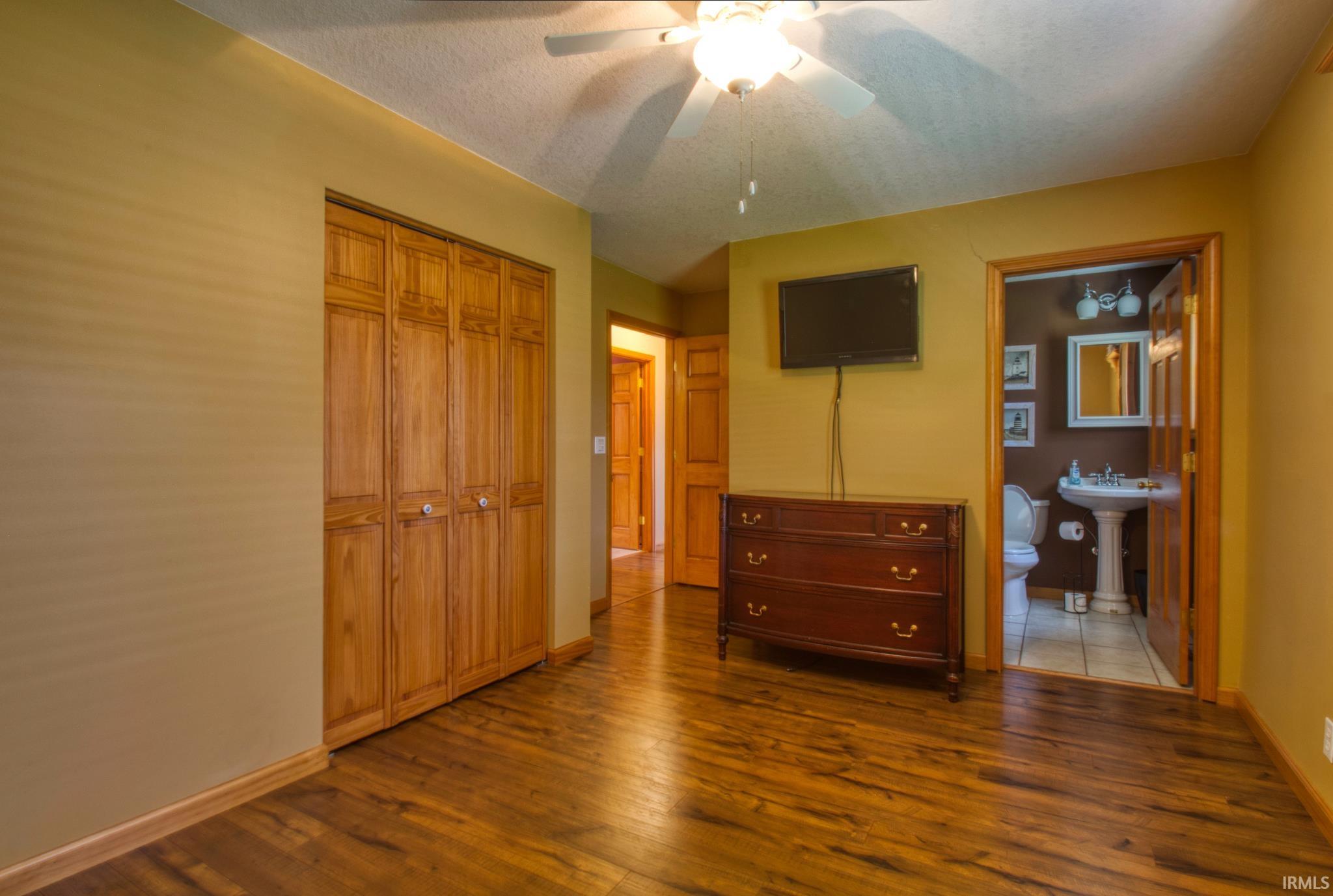 Room featuring warm-toned walls, wood-finish flooring, and a ceiling fan with integrated lighting