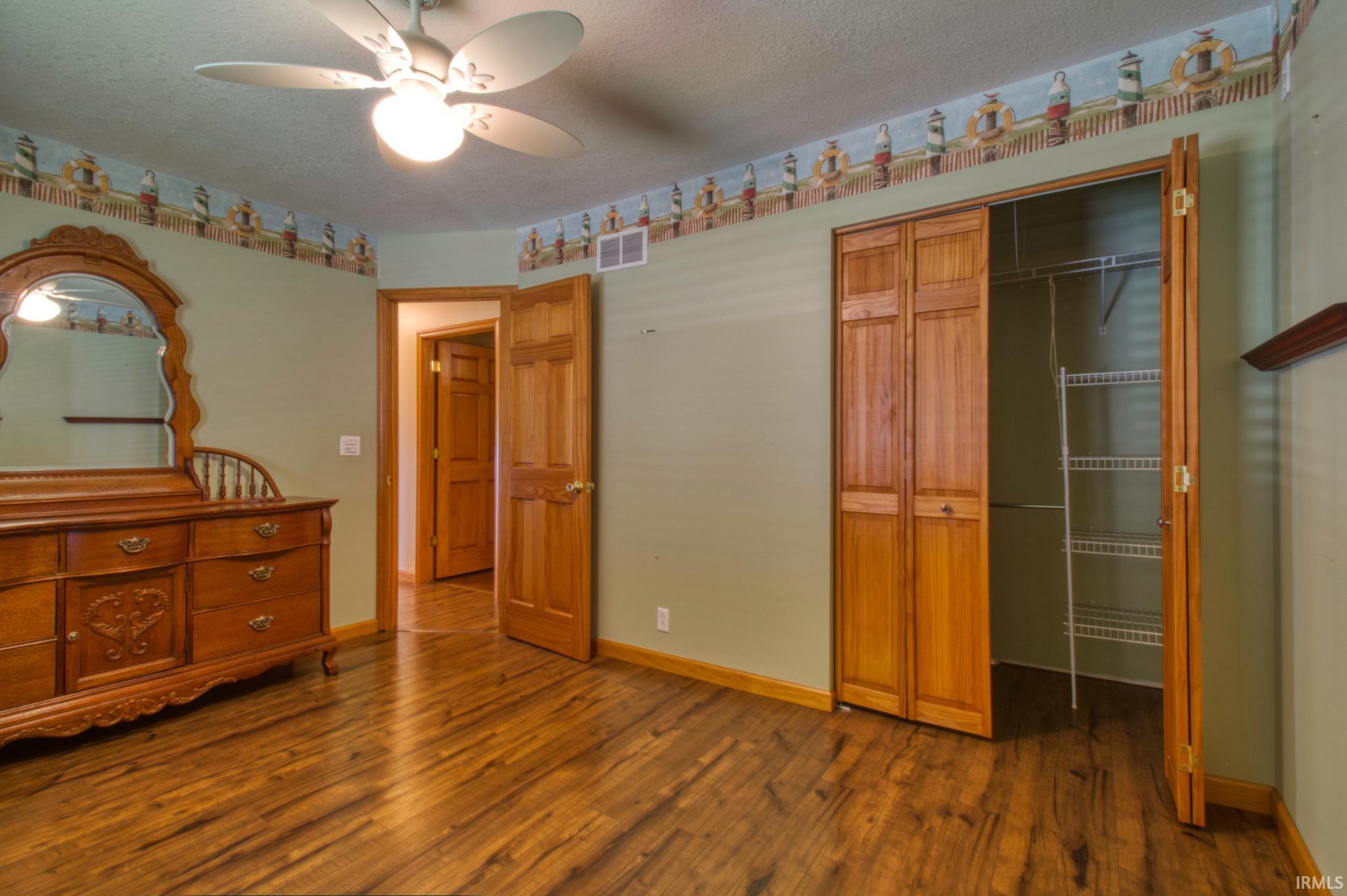 Spacious room featuring wood-finish flooring, light green walls, and a ceiling fan