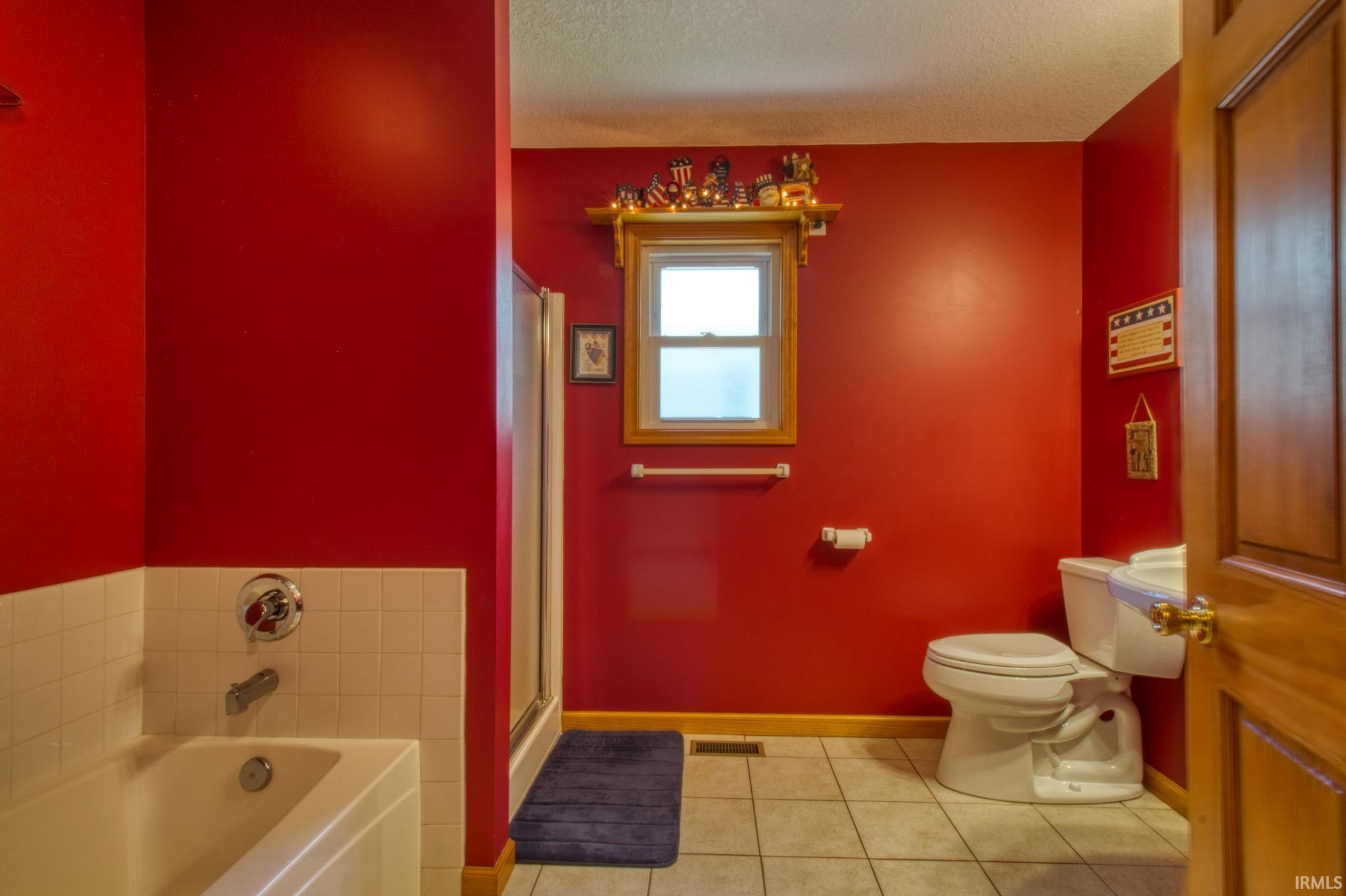 Bathroom featuring a white built-in bathtub with chrome fixtures, a glass-enclosed shower, and a white toilet