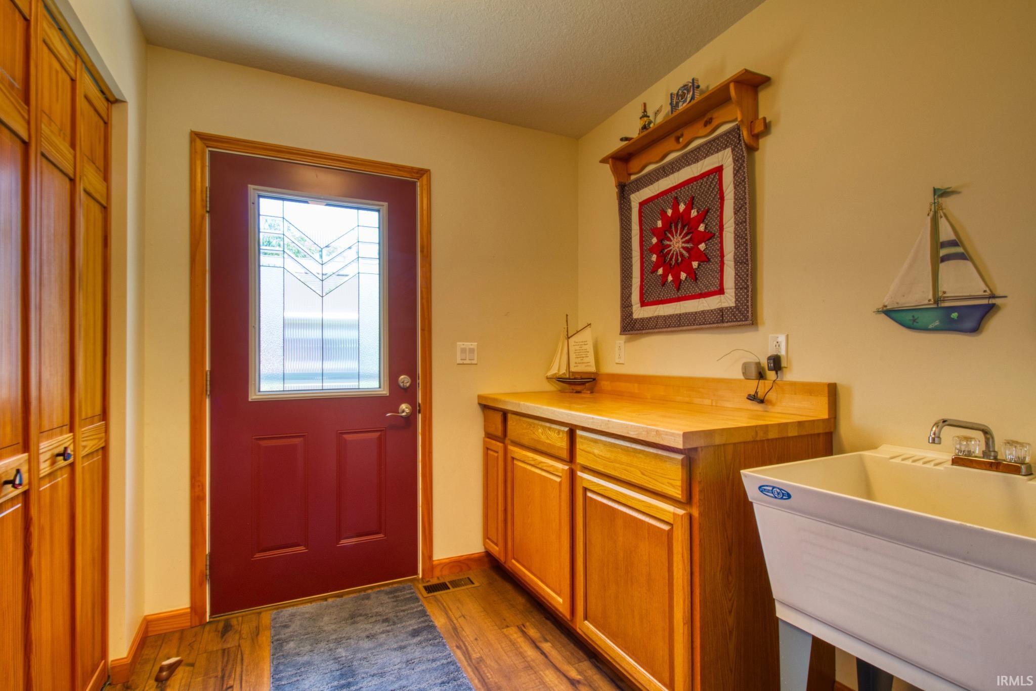 Entryway featuring a red door with decorative glass, wood-finish flooring, and light-toned walls