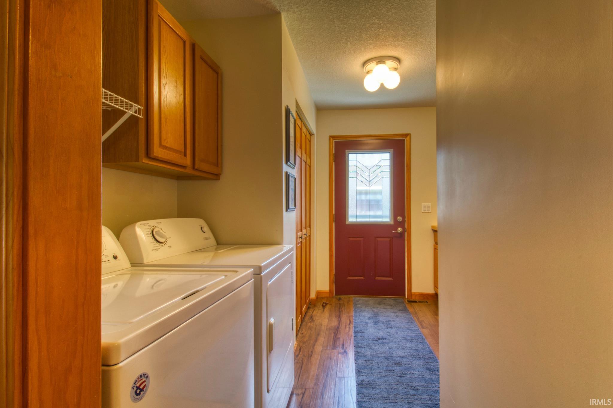 Dedicated laundry area featuring upper wood cabinetry and a wire shelf
