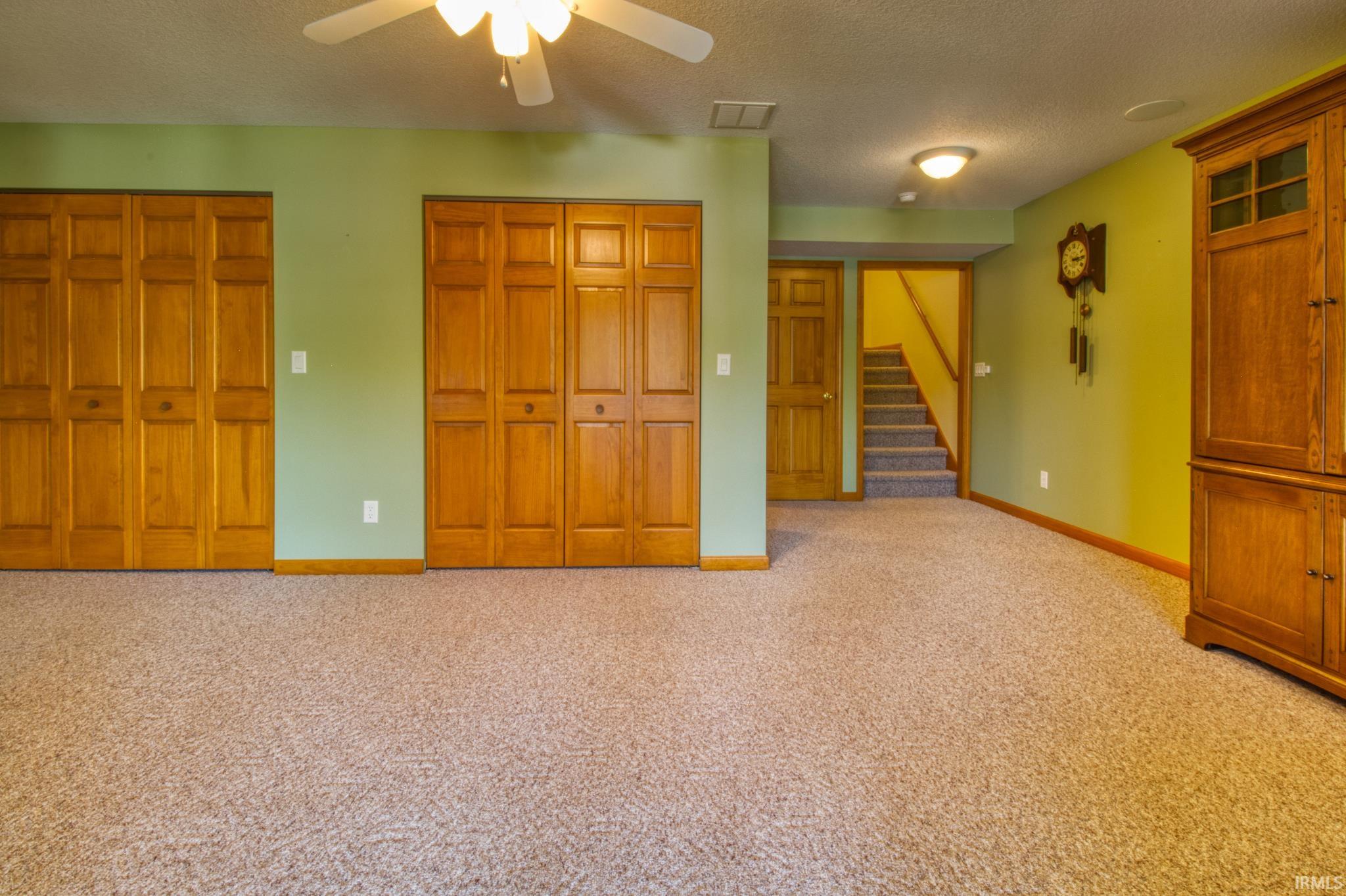 Carpeted interior space featuring light green wall paint and natural wood-finish bi-fold doors