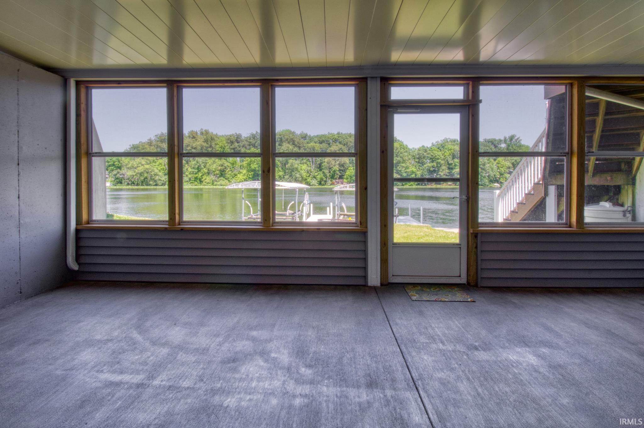 Porch with concrete flooring and wood-frame windows, offering expansive lake scenery
